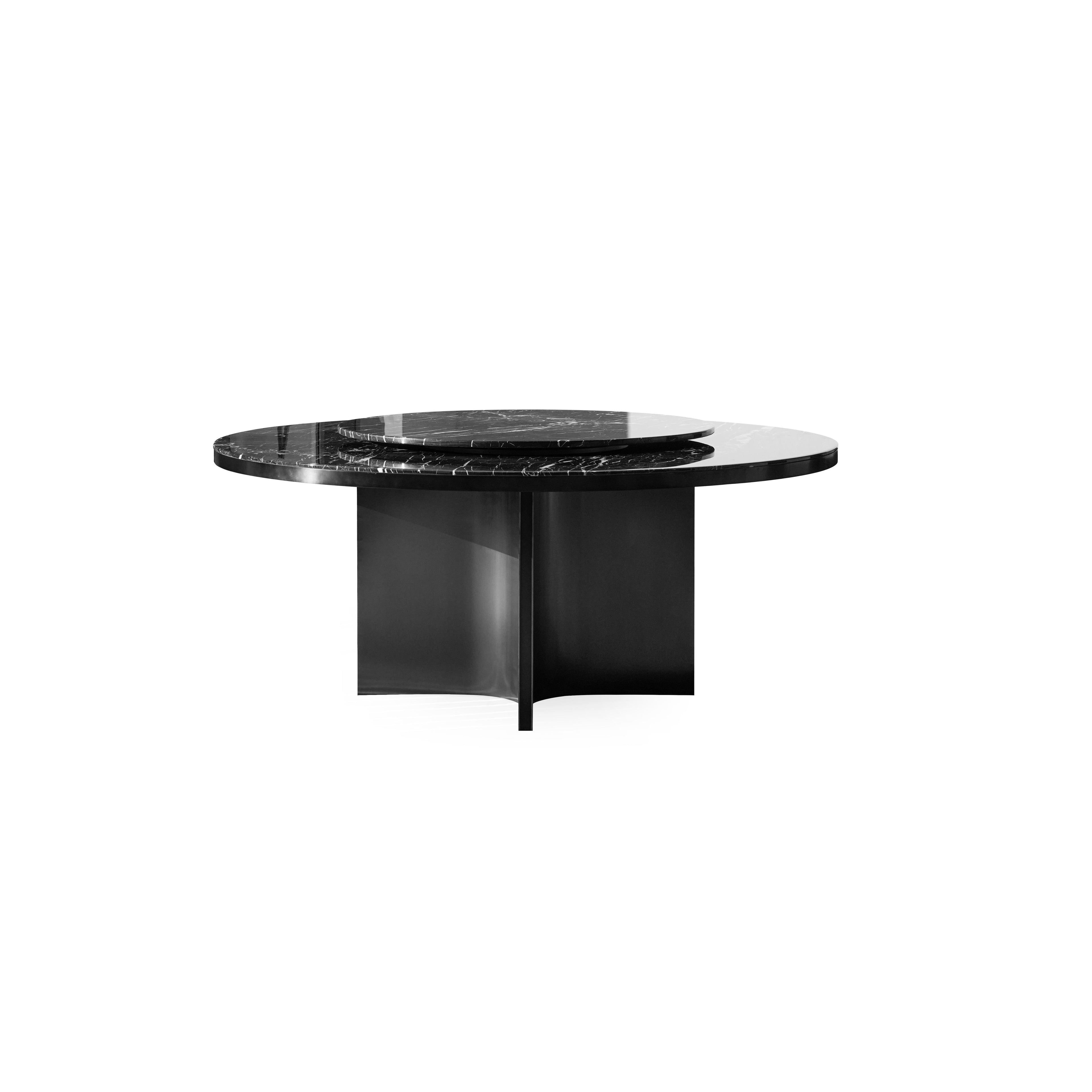 Round dining table with dark gray marble top and matte black metal base featuring three curved legs. Smooth, polished surface with natural veining. Structurally supported by central pillar and side supports. Intended for dining or serving. Category: furniture/dining-tables