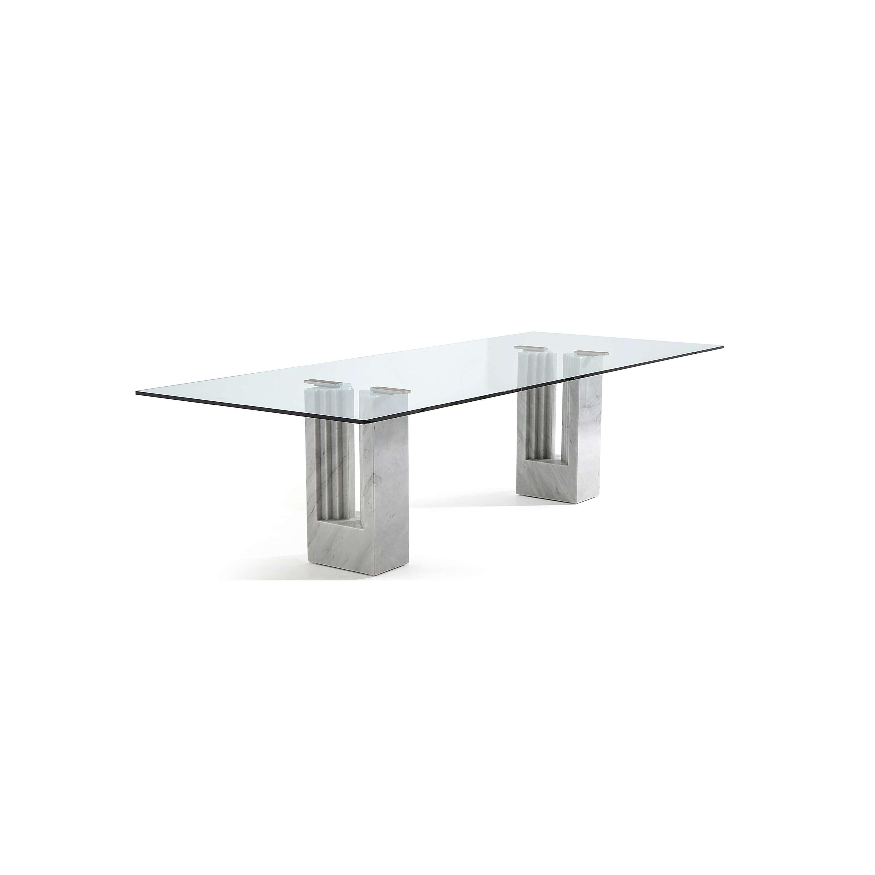 Rectangular glass tabletop supported by two marble bases with vertical grooves and metallic connectors, designed for dining or display, featuring a smooth, polished surface and natural stone texture. Category: Furniture > Tables > Dining Tables