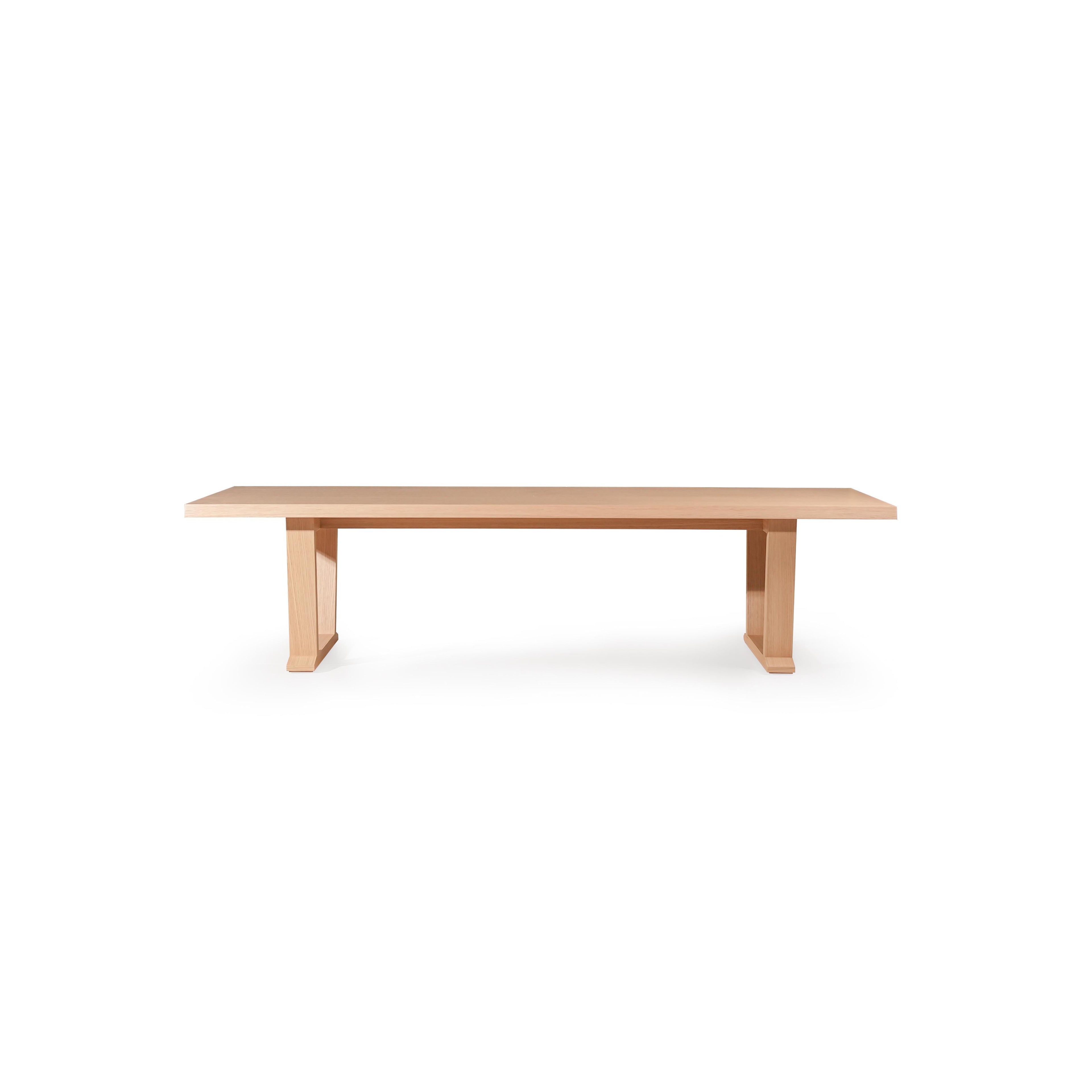 Long rectangular dining table with light wood finish, featuring two U-shaped legs supporting a flat tabletop; minimalistic design with no visible hardware or embellishments, intended for dining or workspace use; Category: furniture/dining-tables