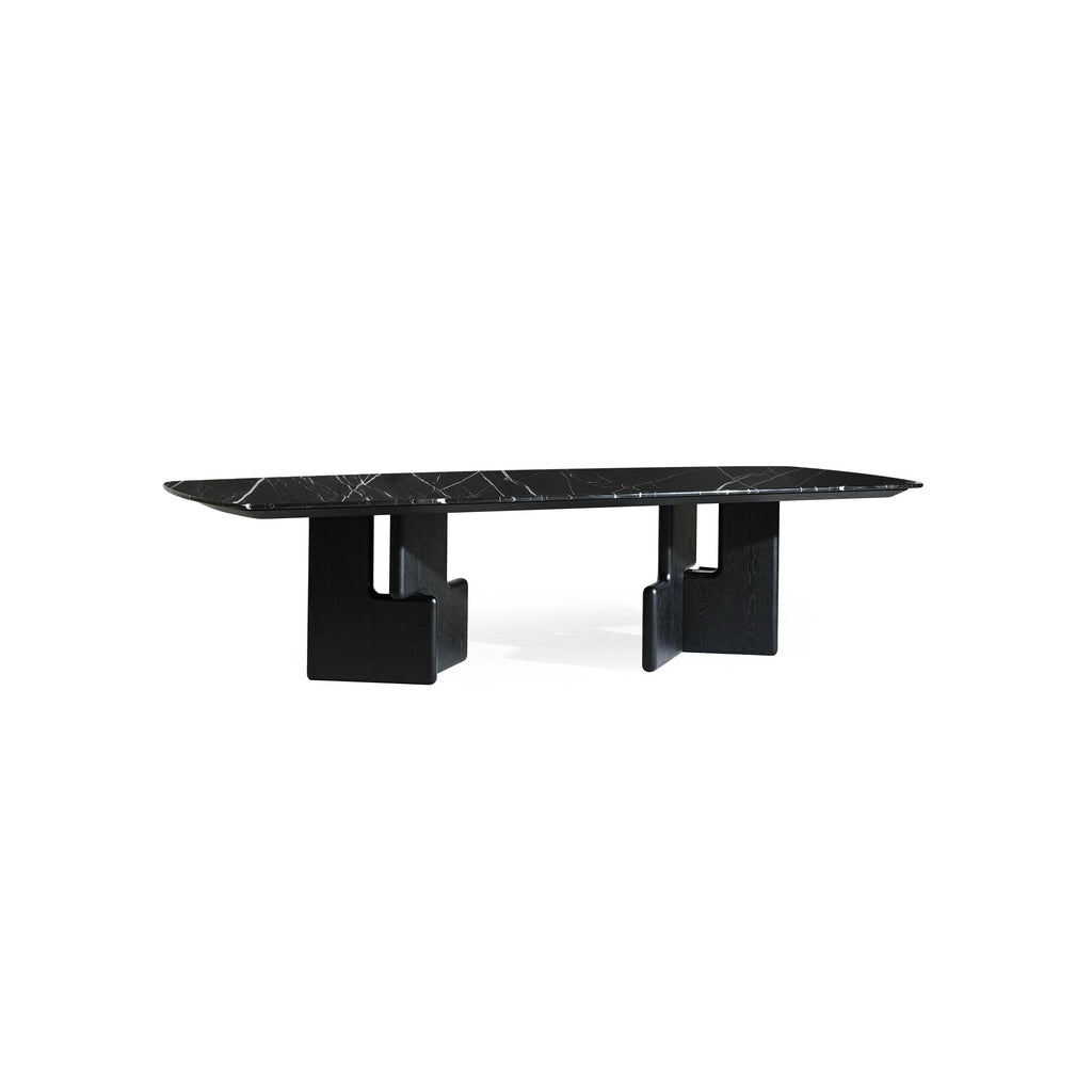 Modern rectangular dining table with black marble top and dark wood legs featuring angular, blocky supports. Table has smooth, flat surface with subtle veining. Intended for dining or serving. Category: furniture/dining-tables