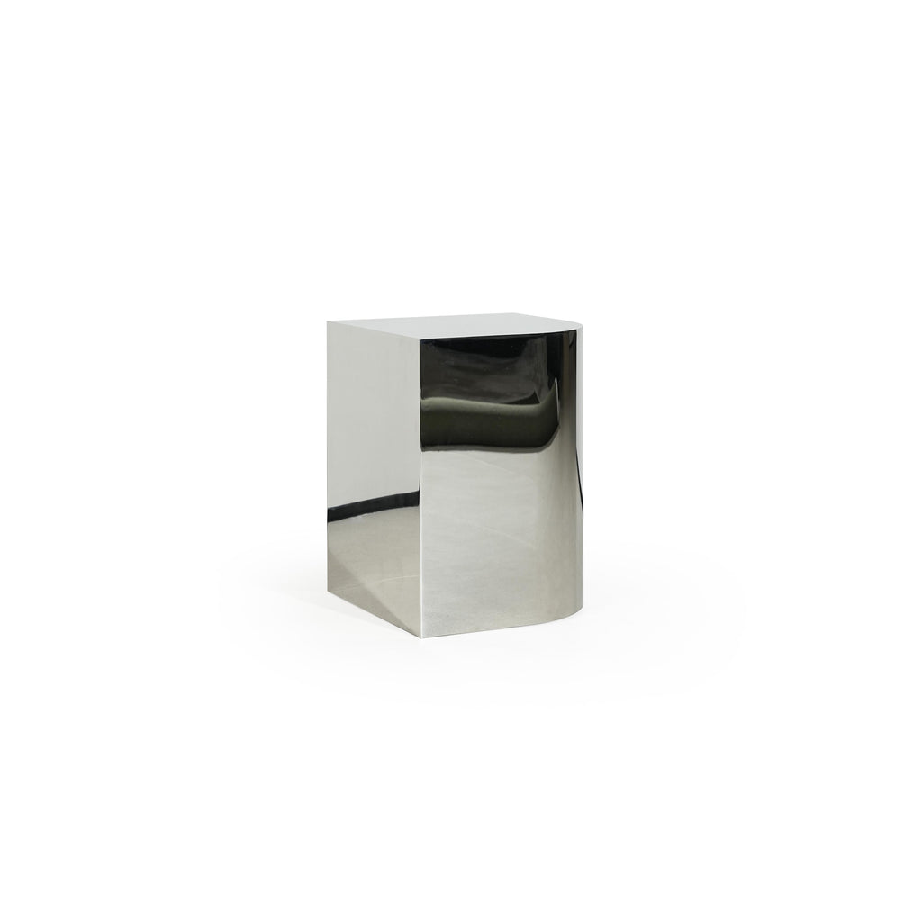 A minimalist side table with a reflective metallic finish, featuring a square top and cylindrical base. It has no visible legs or handles, constructed from a single continuous piece. Intended for placing items beside seating. Category: furniture/stools-and-side-tables
