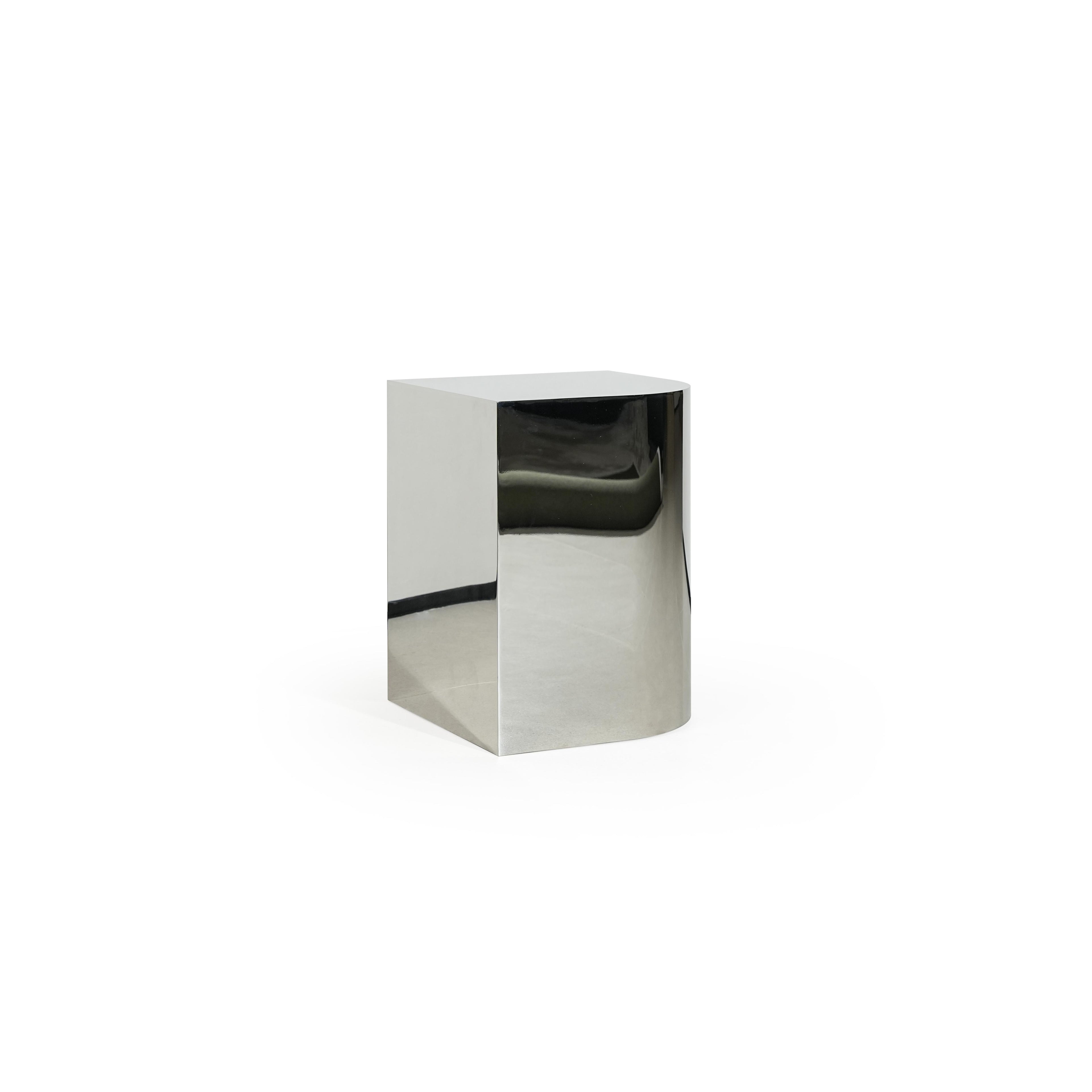 A minimalist side table with a reflective metallic finish, featuring a square top and cylindrical base. It has no visible legs or handles, constructed from a single continuous piece. Intended for placing items beside seating. Category: furniture/stools-and-side-tables