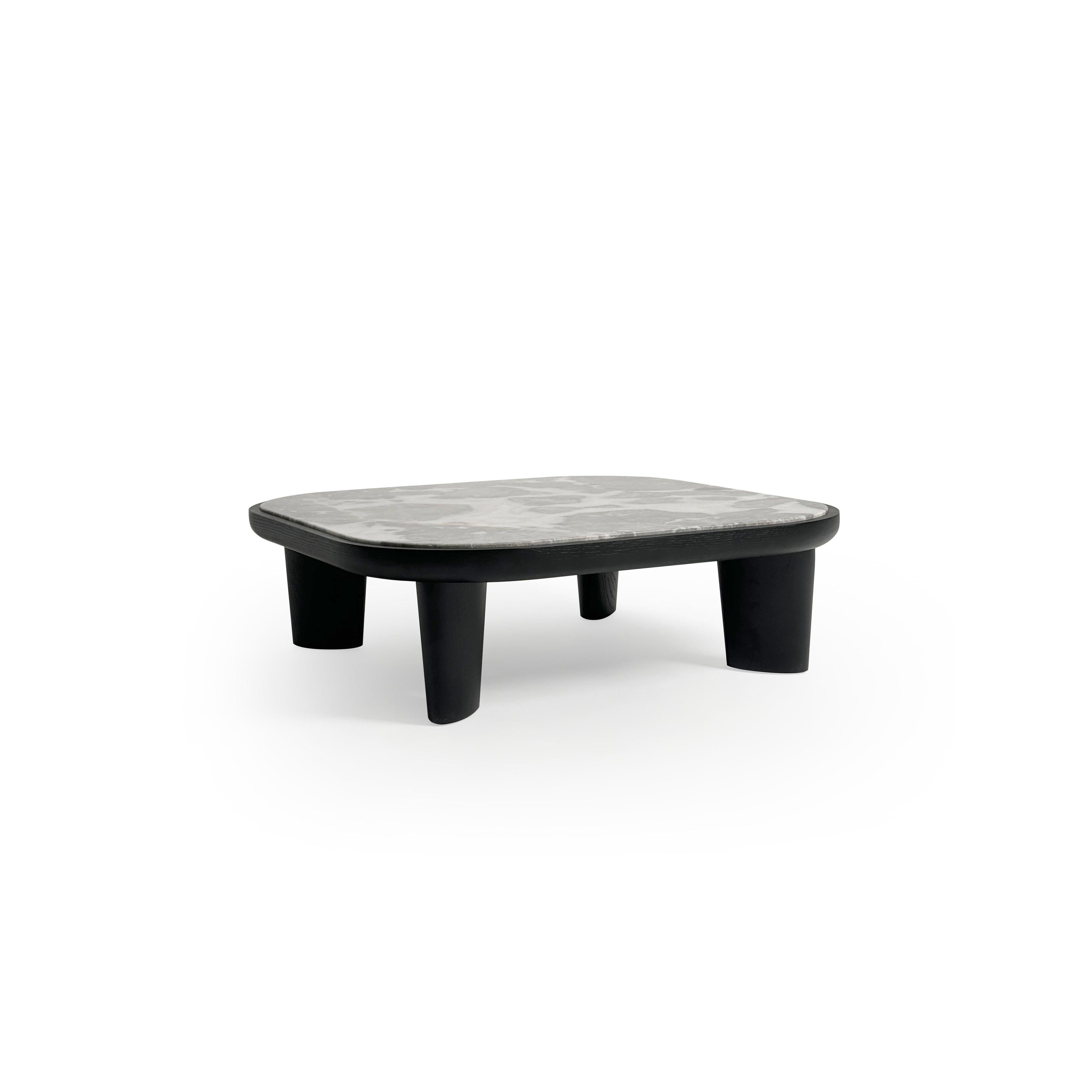 Low-profile coffee table with rounded rectangular top in light gray marble-like surface, supported by four thick, dark-stained wooden legs. Minimalist design for placing items on a flat surface. Category: furniture/coffee-tables