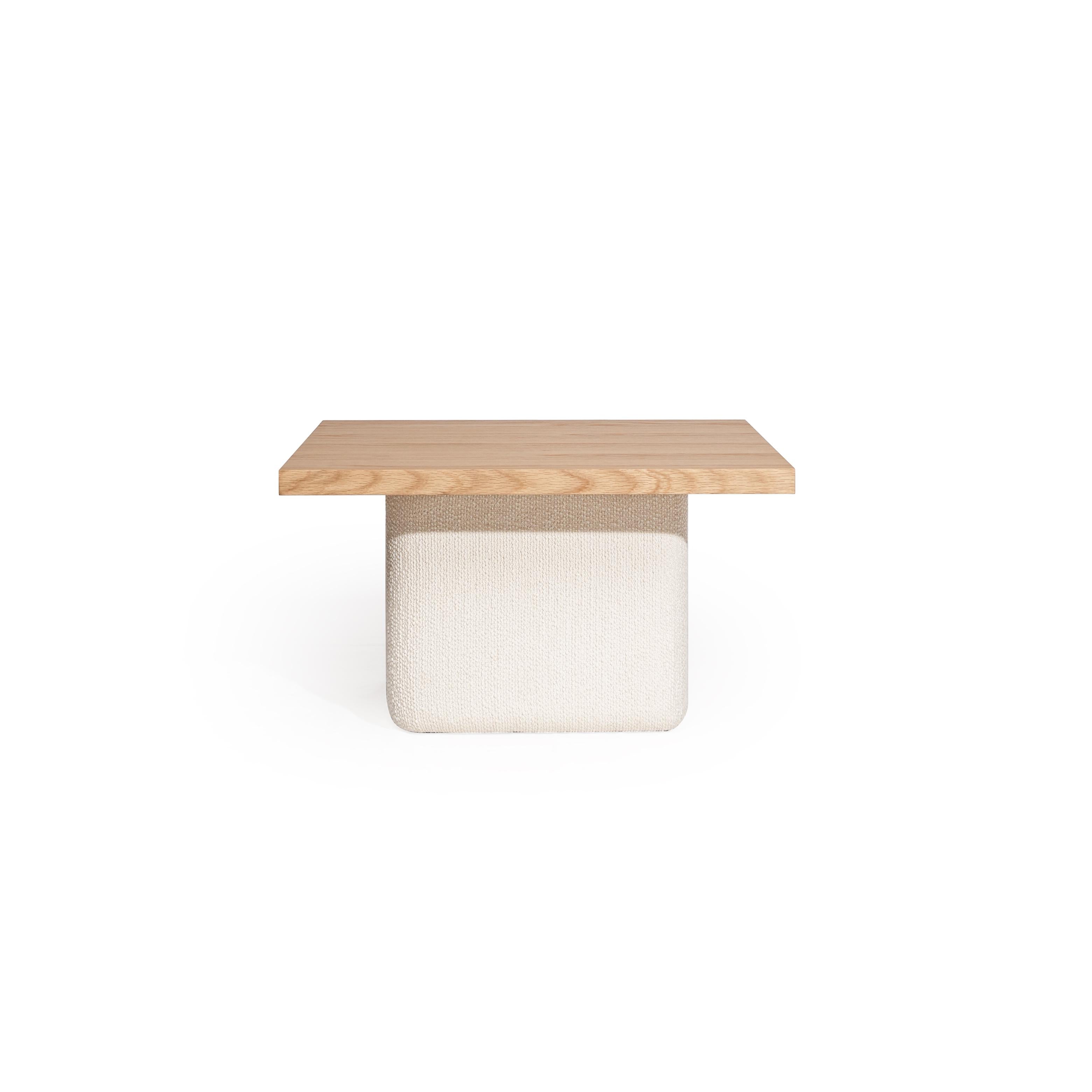 Square-top table with dark wood surface and textured off-white base, featuring a distinct fabric-wrapped pedestal structure, designed for surface placement or as a low seating option, marked with a small tag on the side. Category: Furniture > Tables > Coffee Tables