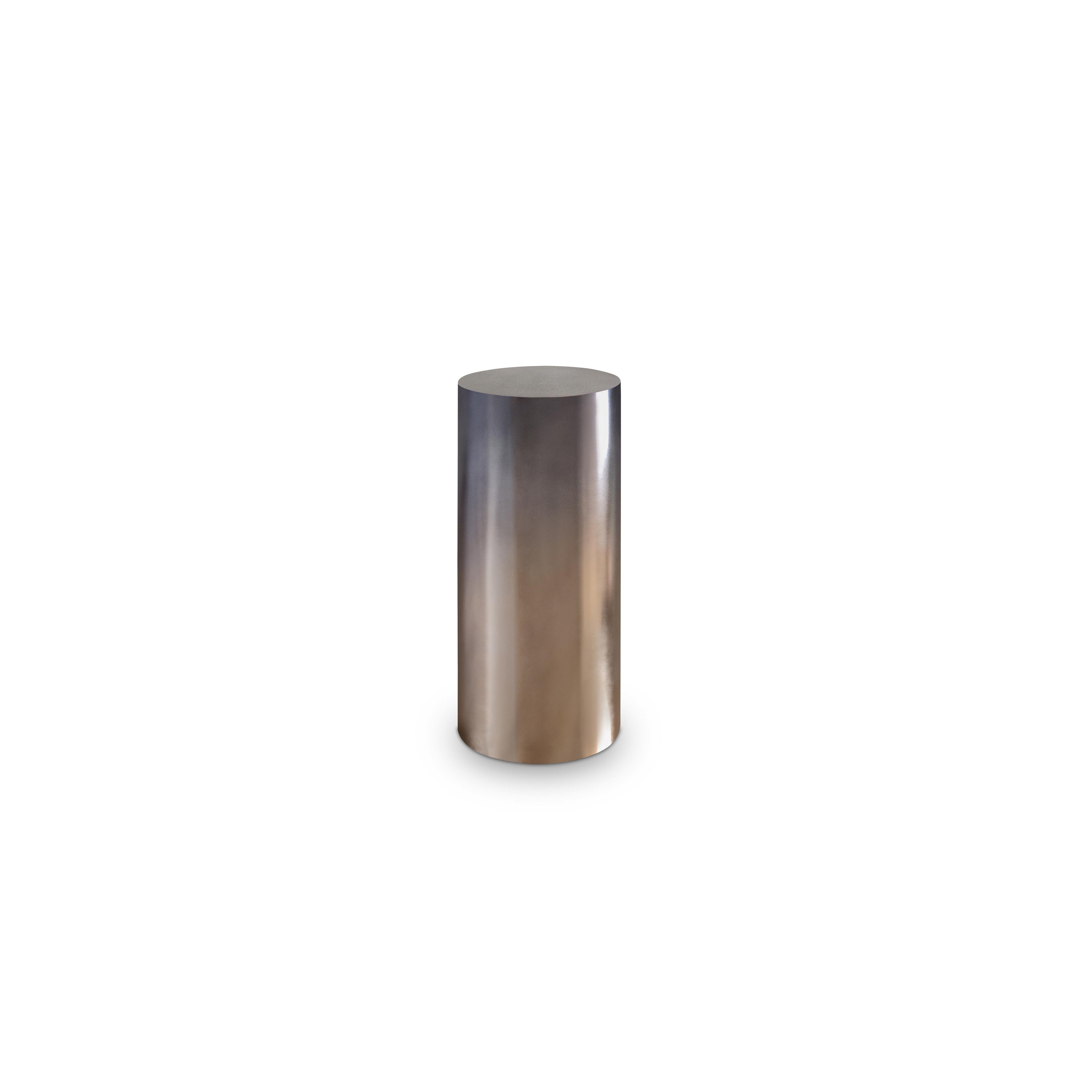 This is a cylindrical side table with a smooth, metallic finish that transitions from silver to bronze. It has no legs, arms, or handles. Its solid, vertical form suggests it’s meant for holding small items. Category: furniture/side-tables