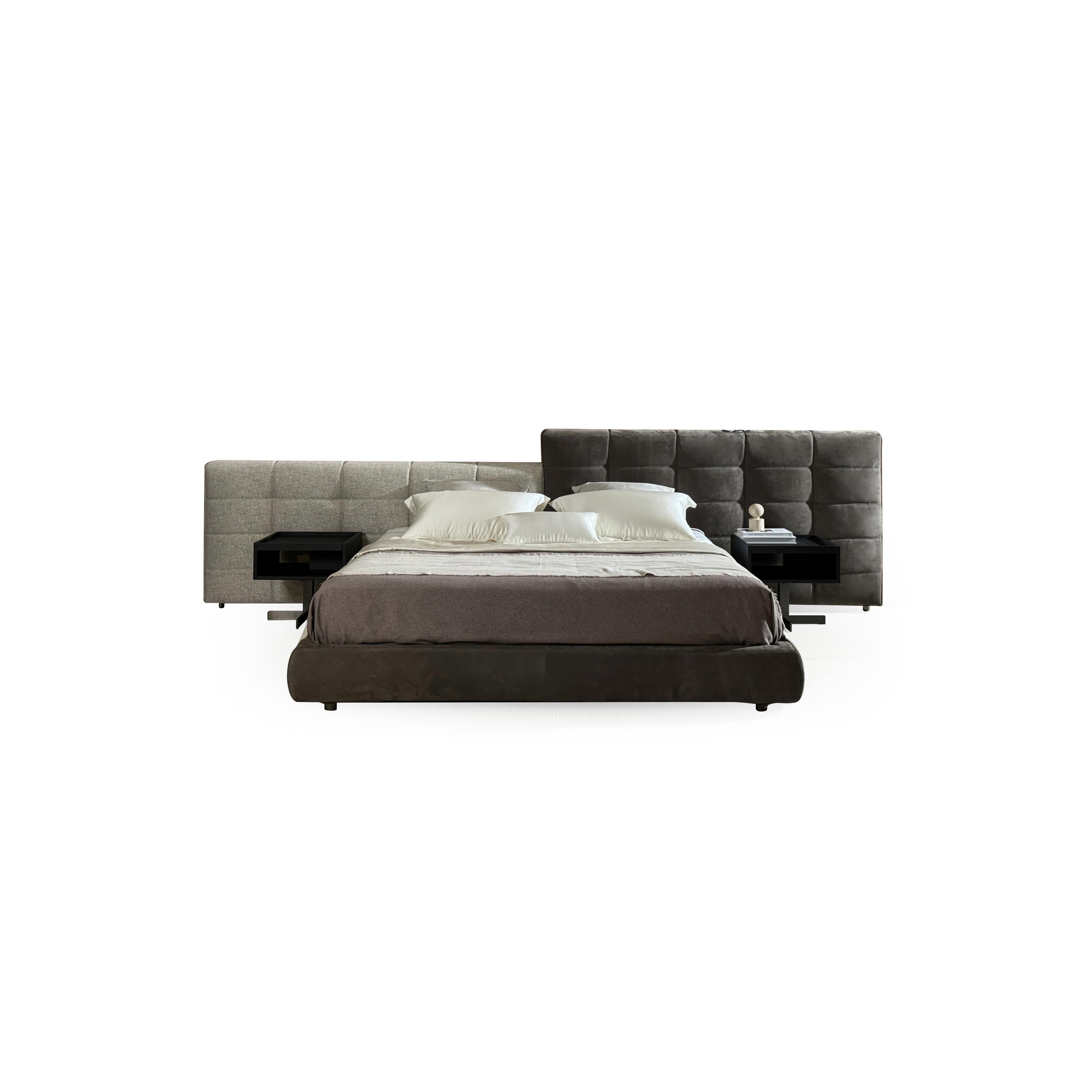 Tufted upholstered bed with two-tone headboard, dark brown base, and light gray side panel; features low-profile frame, four short legs, and layered pillows on mattress; fabric upholstery with visible stitching; intended for sleeping; Category: furniture > beds > upholstered beds