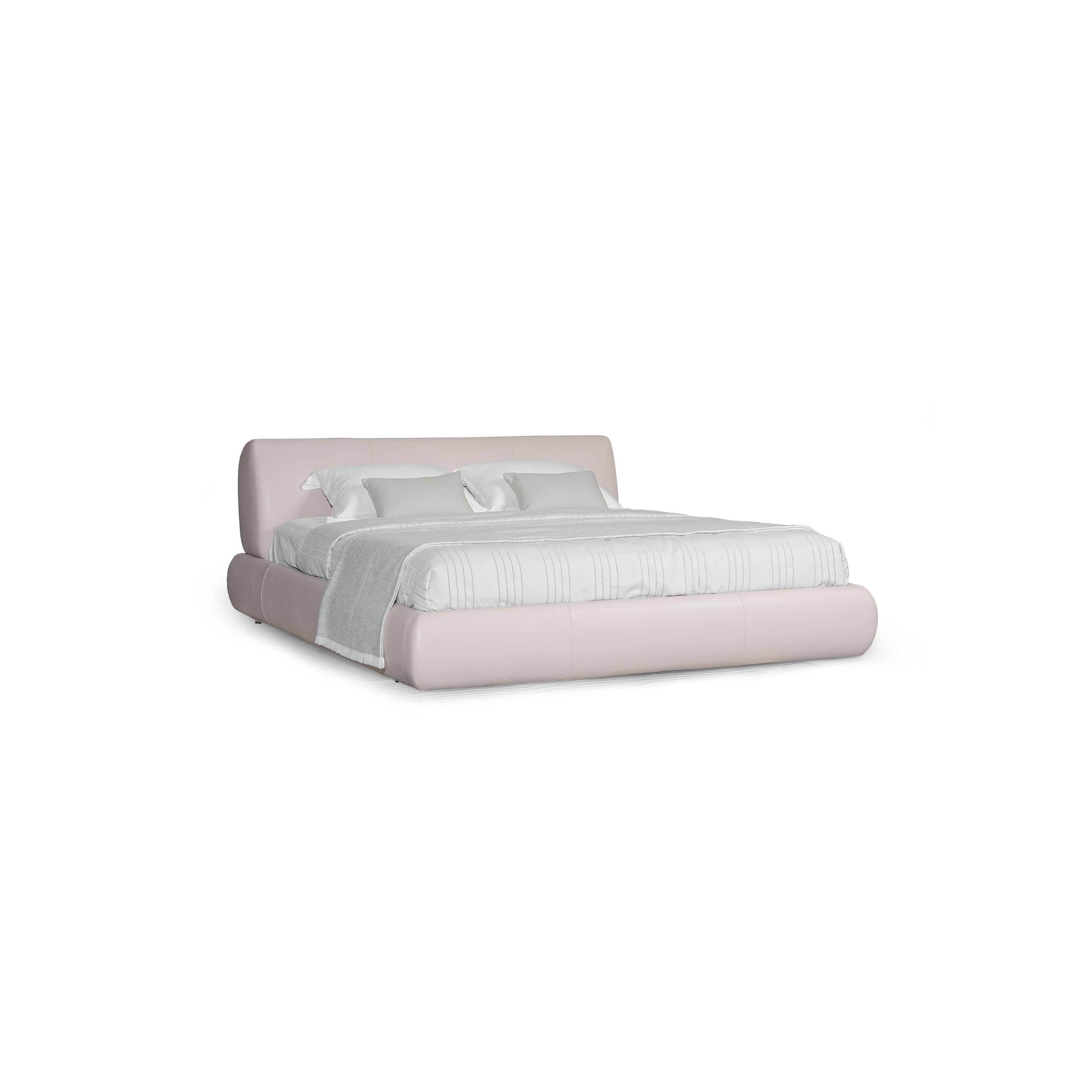 Low-profile platform bed with upholstered headboard and base in muted taupe fabric. Features padded cushions, subtle stitching, and short black legs. Designed for sleeping, with two white pillows and a light gray throw blanket. Category: furniture > beds > platform beds