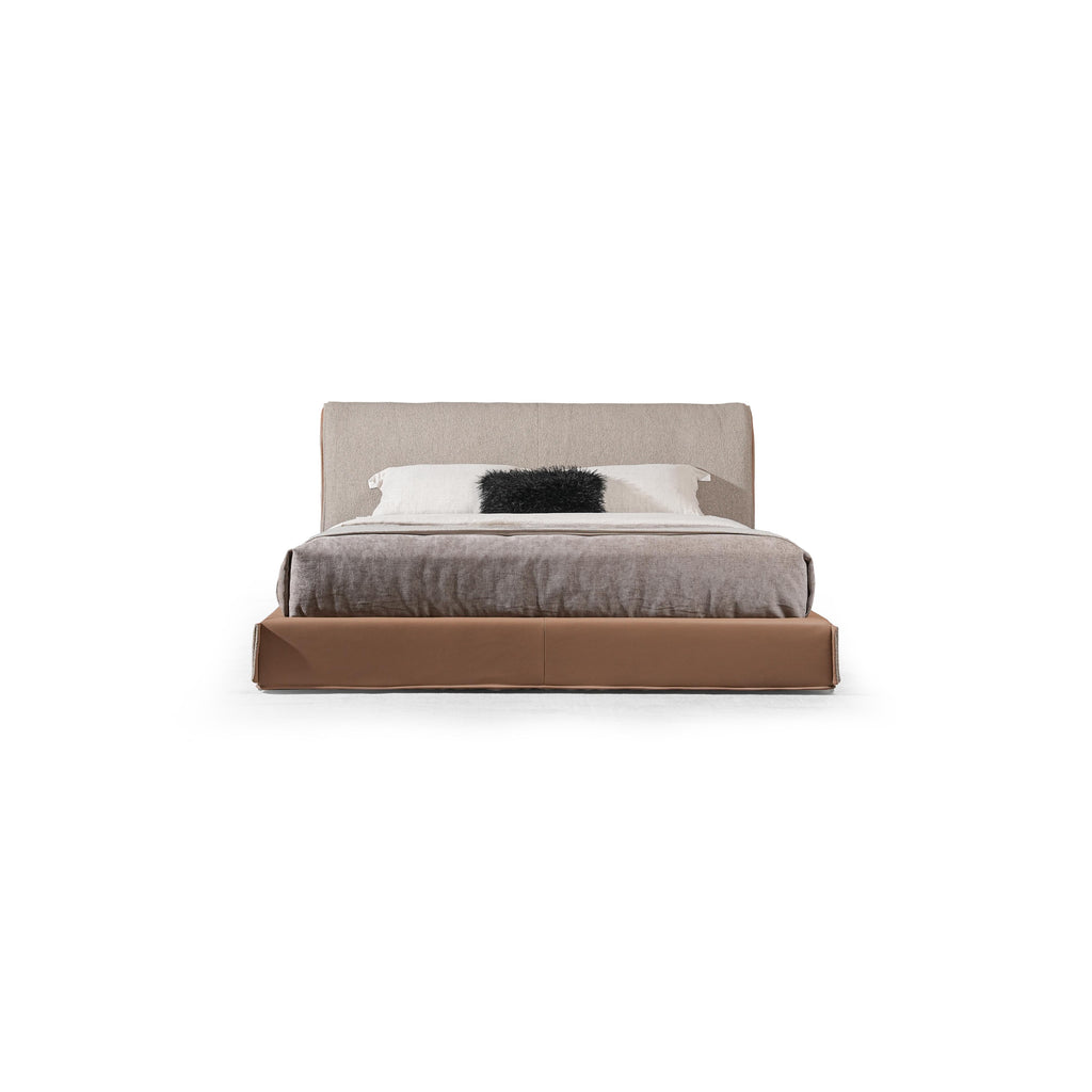 Low-profile bed with upholstered headboard and base, featuring beige fabric headboard, brown base, gray textured comforter, and white pillow with black furry accent; designed for sleeping, with clean lines and visible seam stitching. Category: furniture > beds > platform beds