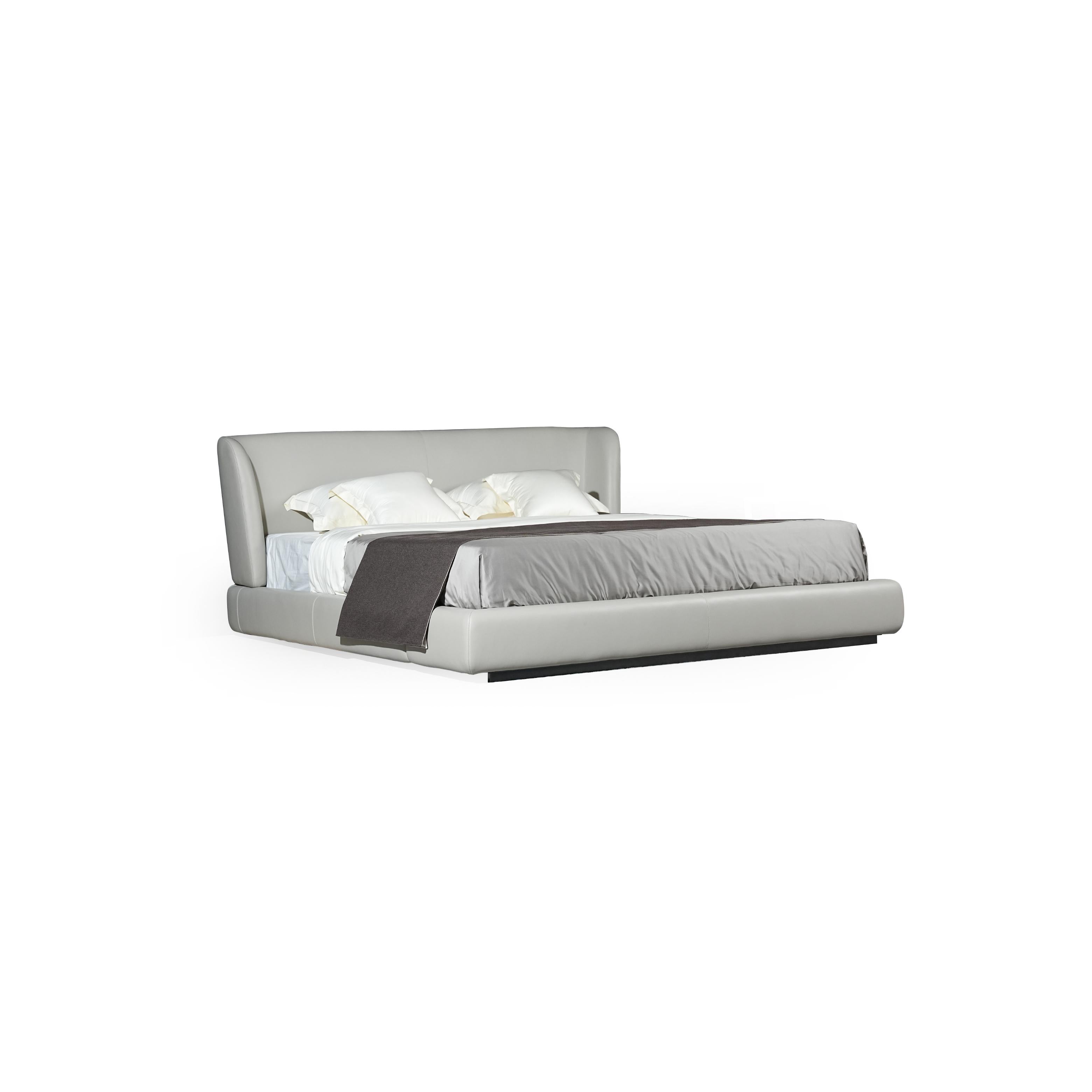 A low-profile bed with a continuous upholstered headboard and base, featuring a light gray fabric surface, two white pillows, and a dark gray throw blanket; supported by a dark base; designed for sleeping; Category: furniture > beds > platform beds