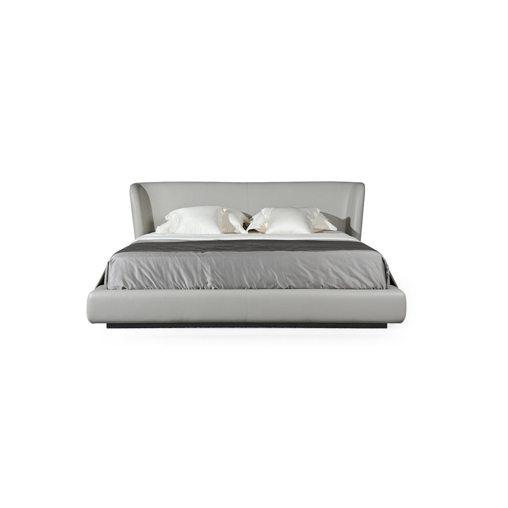 A low-profile bed with a continuous upholstered headboard and base, featuring a light gray fabric surface, two white pillows, and a dark gray throw blanket; supported by a dark base; designed for sleeping; Category: furniture > beds > platform beds