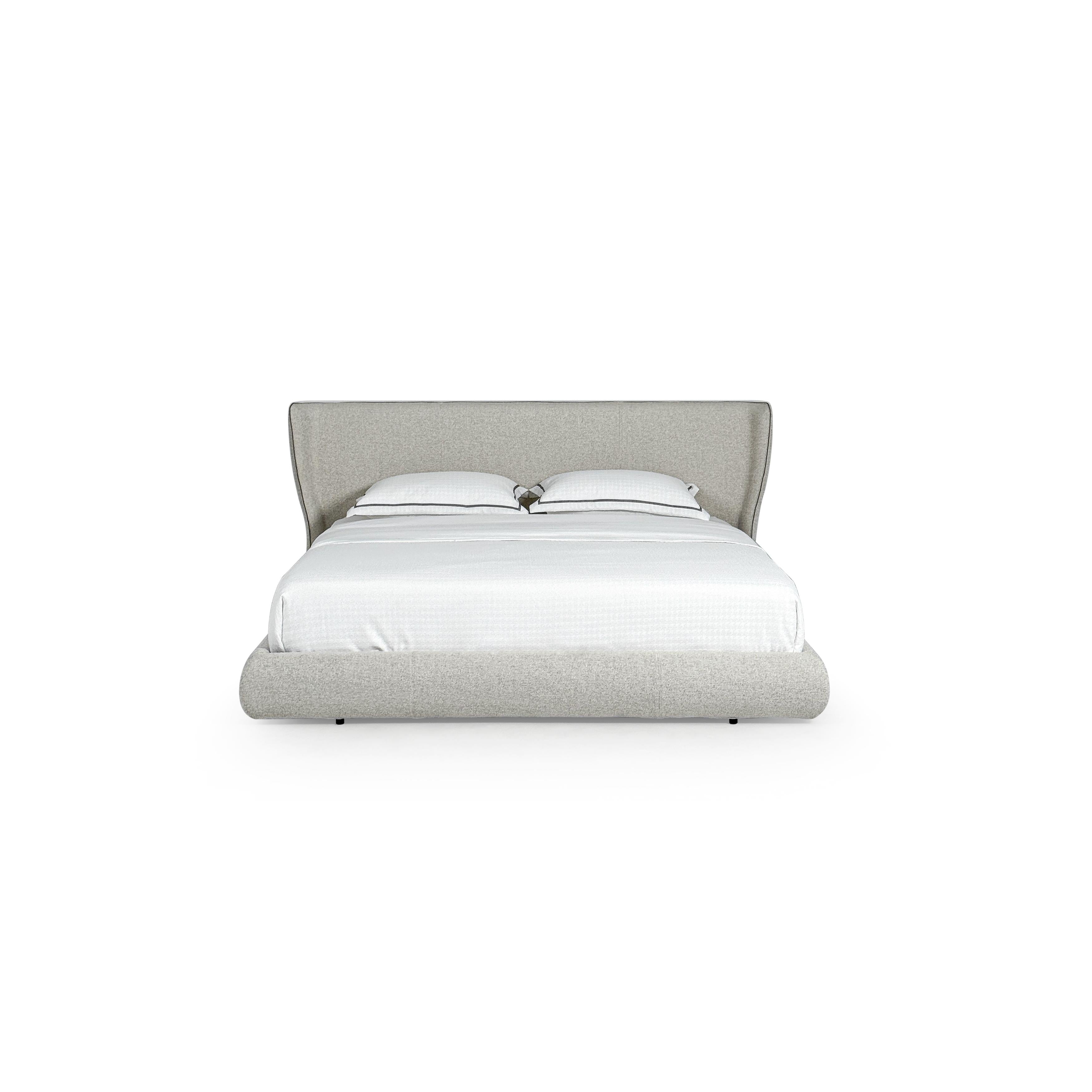 This upholstered bed features a low-profile frame with a padded headboard and base, covered in a light gray textured fabric. It includes two white pillows with dark trim and a white quilted mattress. Designed for sleeping, it has small black feet. Category: furniture > beds > upholstered beds
