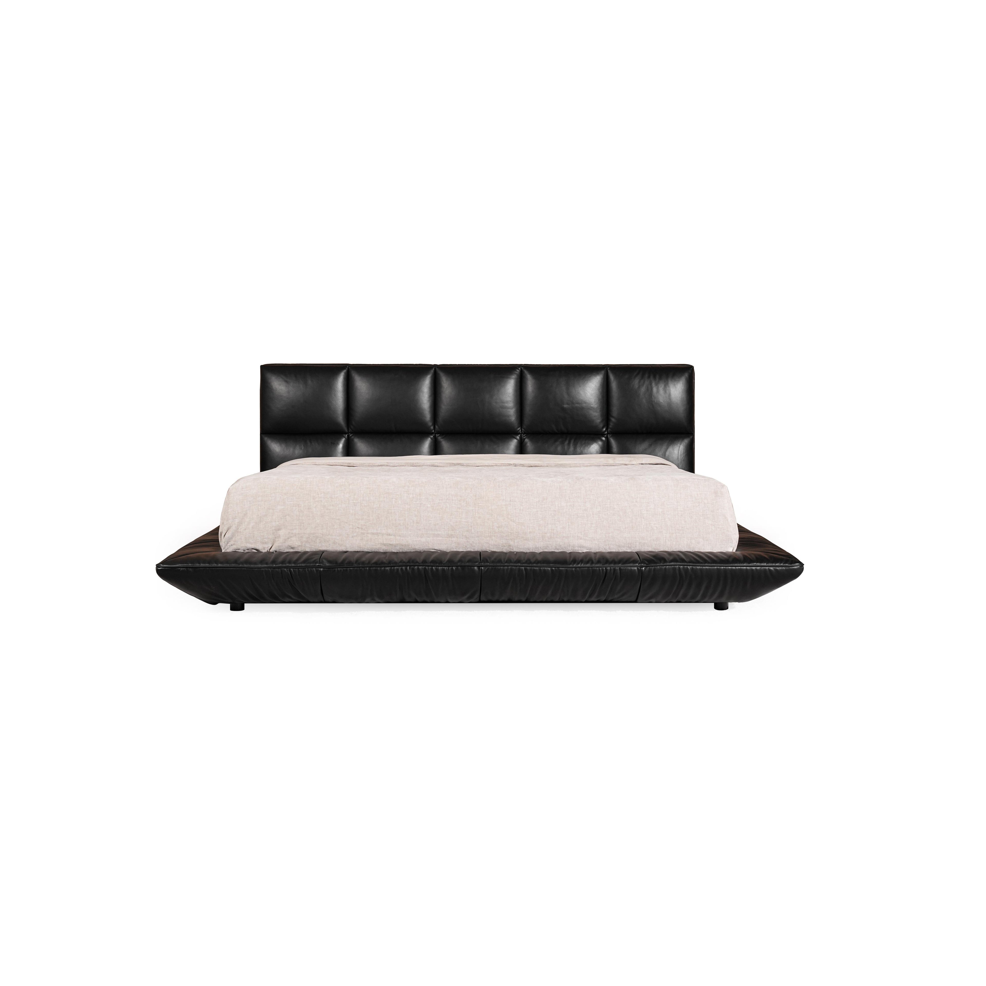 Black leather-like upholstered bed with tufted headboard and matching base, featuring low-profile legs and stitched seams; light-colored bedding rests atop; designed for sleeping; Category: furniture > beds > platform beds