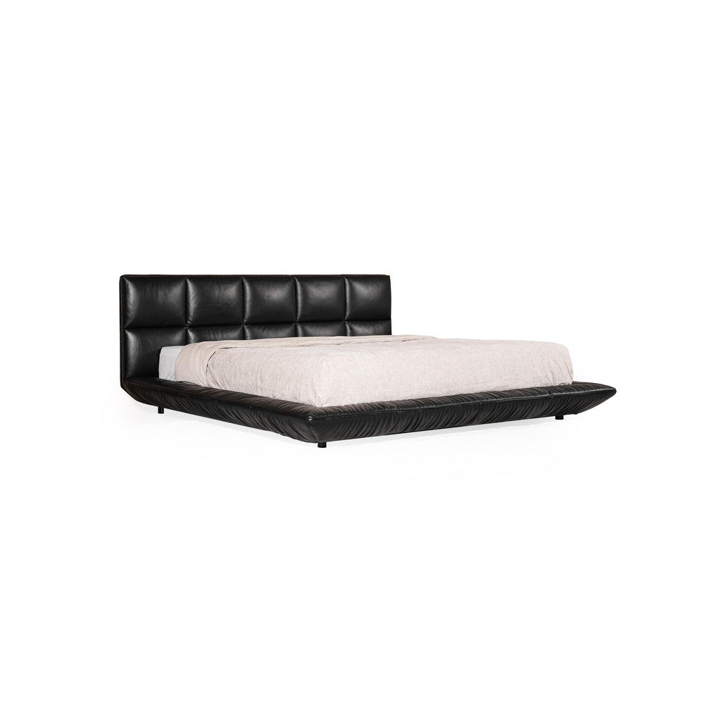 Black leather-like upholstered bed with tufted headboard and matching base, featuring low-profile legs and stitched seams; light-colored bedding rests atop; designed for sleeping; Category: furniture > beds > platform beds