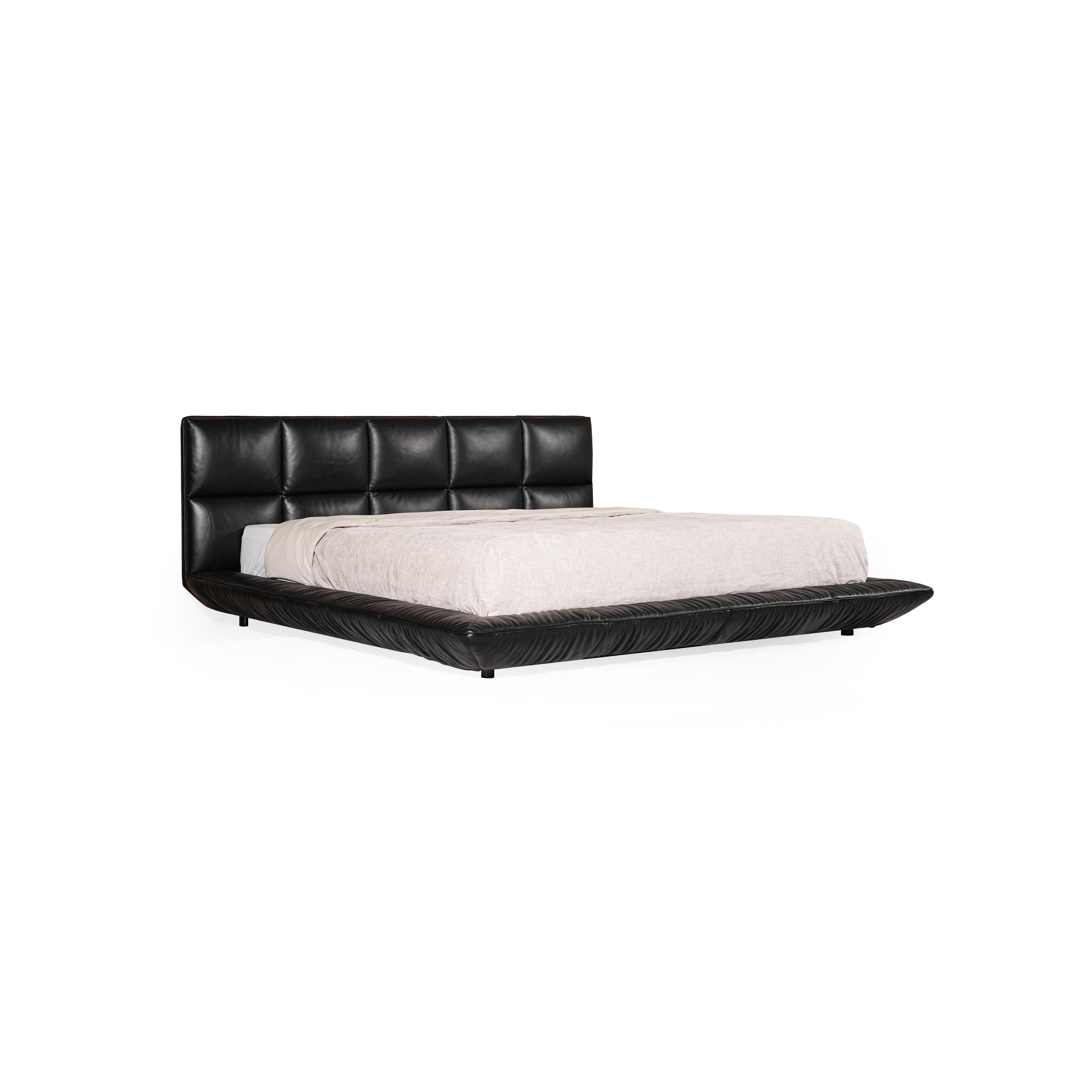 Black leather-like upholstered bed with tufted headboard and matching base, featuring low-profile legs and stitched seams; light-colored bedding rests atop; designed for sleeping; Category: furniture > beds > platform beds