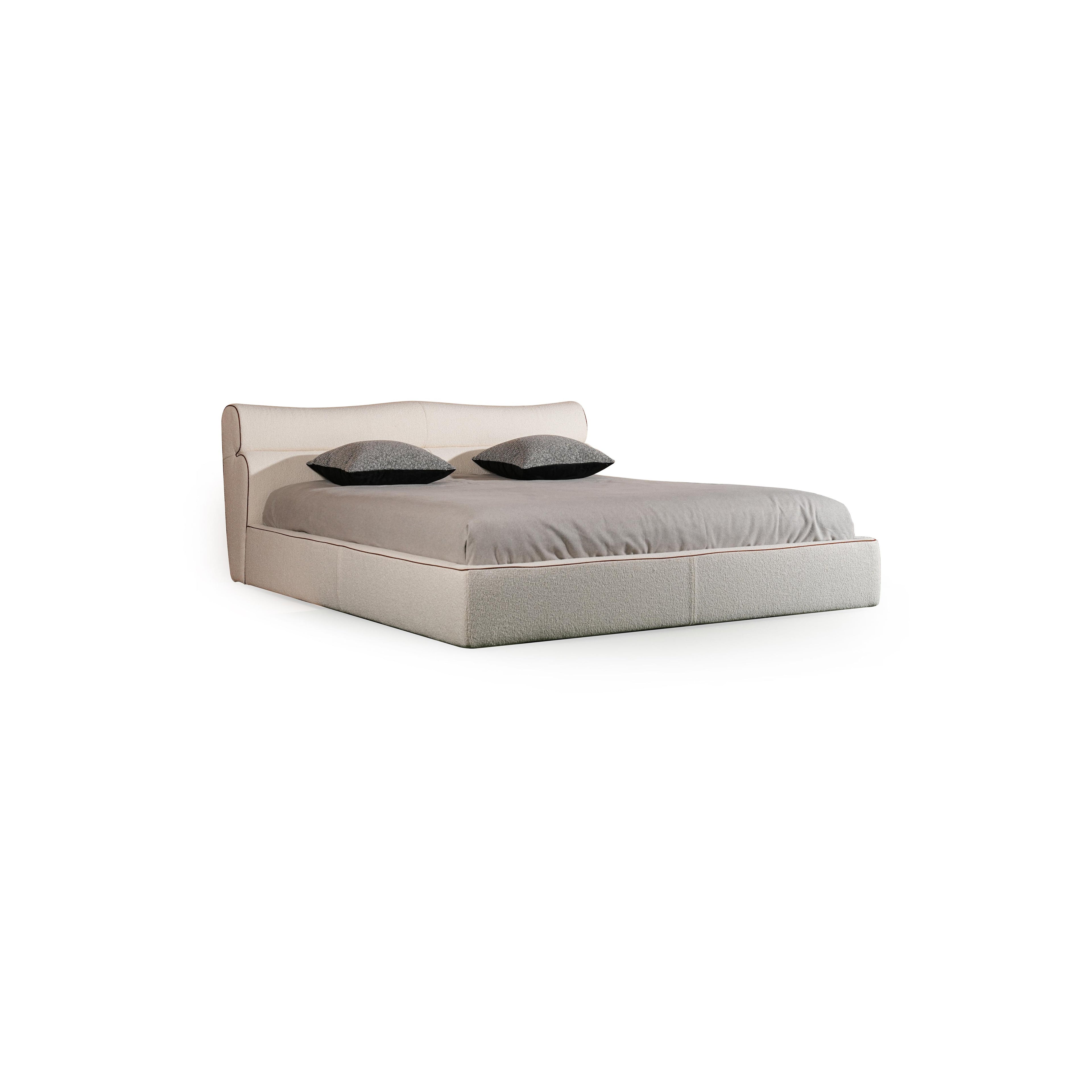 Upholstered bed with a low-profile rectangular frame, featuring a padded headboard and base, covered in a textured fabric with subtle stitching. Two dark gray pillows rest on the mattress. Category: furniture > beds > upholstered beds