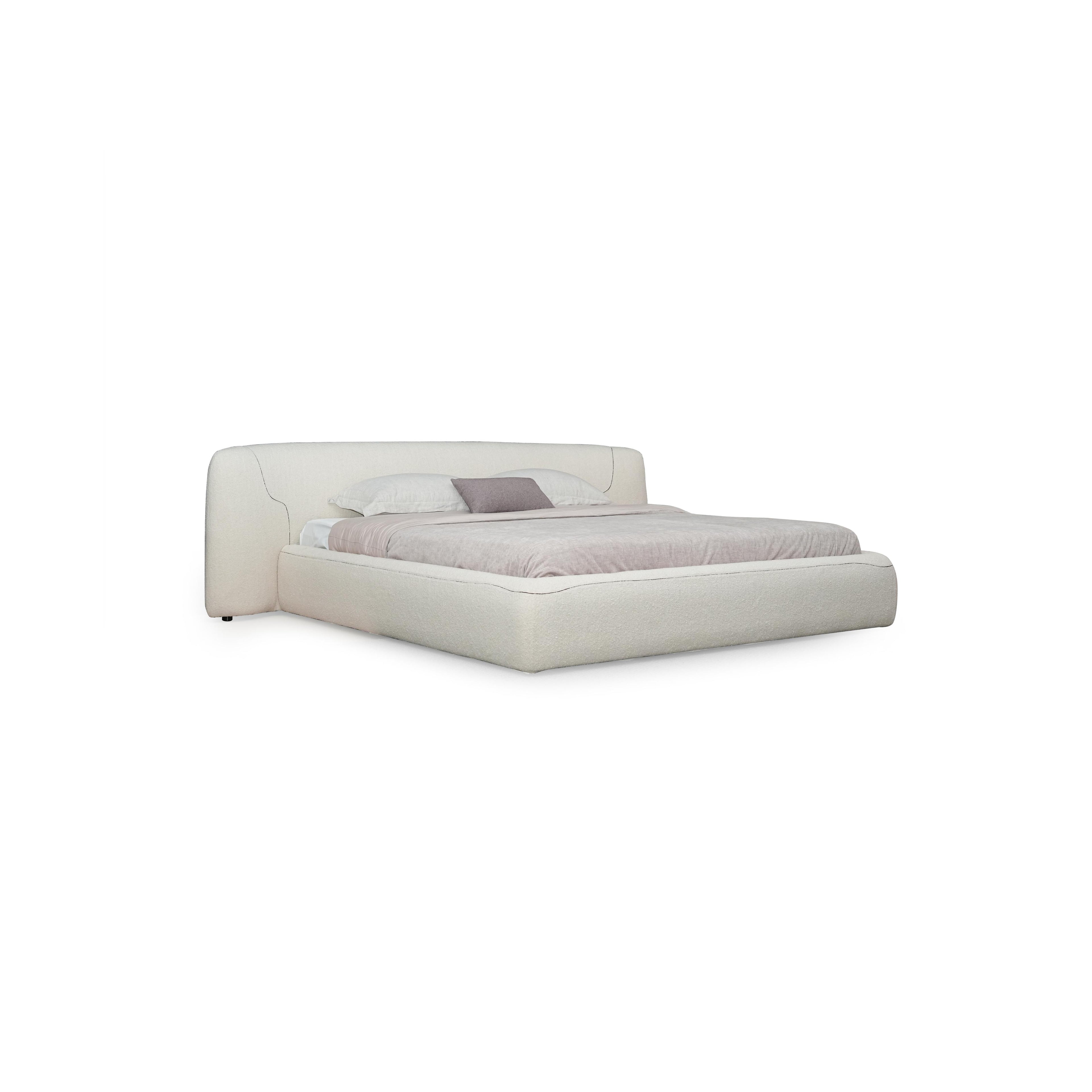 Upholstered bed with a low-profile, rectangular frame and a padded headboard featuring subtle stitched seams. Covered in a light beige fabric, it includes two white pillows and one gray accent pillow. Designed for sleeping, it has no visible legs or hardware. Category: furniture > beds > upholstered beds