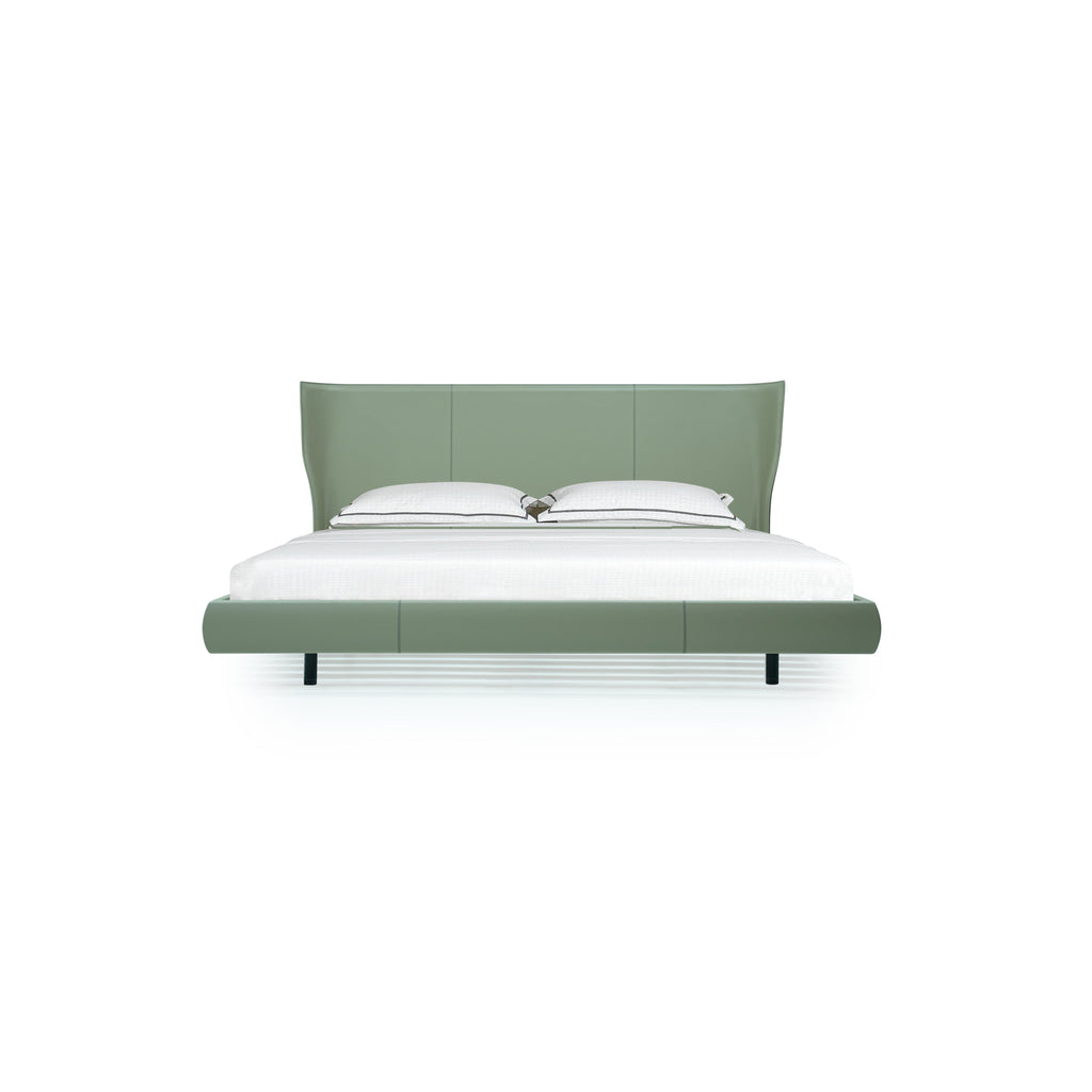 A modern bed with a sage green upholstered headboard and base, featuring two black legs, white pillows with dark piping, and a white mattress; designed for sleeping, with clean lines and stitched paneling on the frame. Category: furniture > beds > platform beds