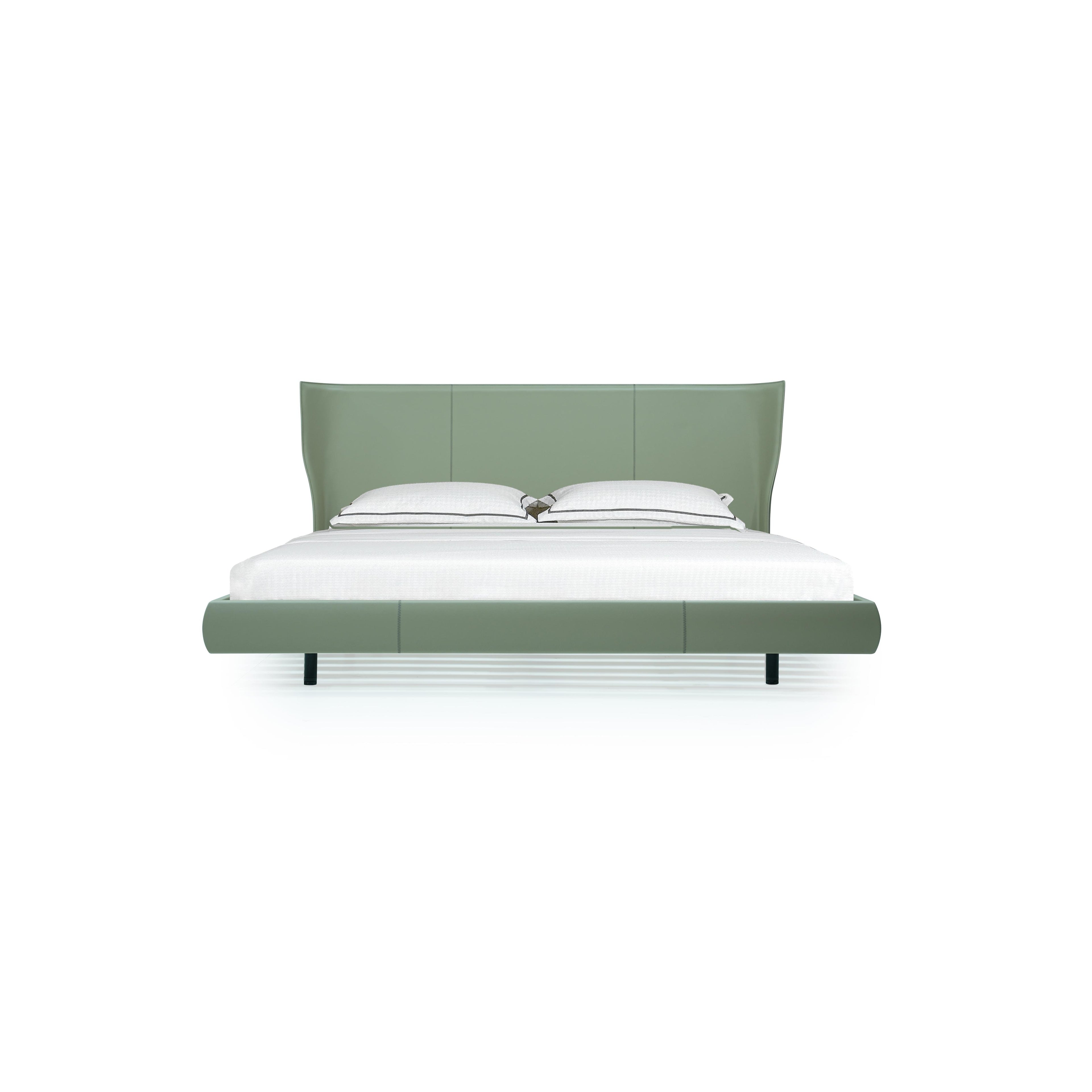 A modern bed with a sage green upholstered headboard and base, featuring two black legs, white pillows with dark piping, and a white mattress; designed for sleeping, with clean lines and stitched paneling on the frame. Category: furniture > beds > platform beds