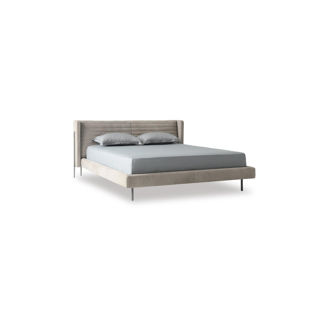 A modern bed with a gray upholstered headboard and base, supported by four thin black legs. It features a tufted backrest, layered pillows, and a satin-textured duvet. Designed for sleeping, it has a clean, minimalist silhouette with visible stitching along seams. Category: Furniture > Beds > Modern Beds