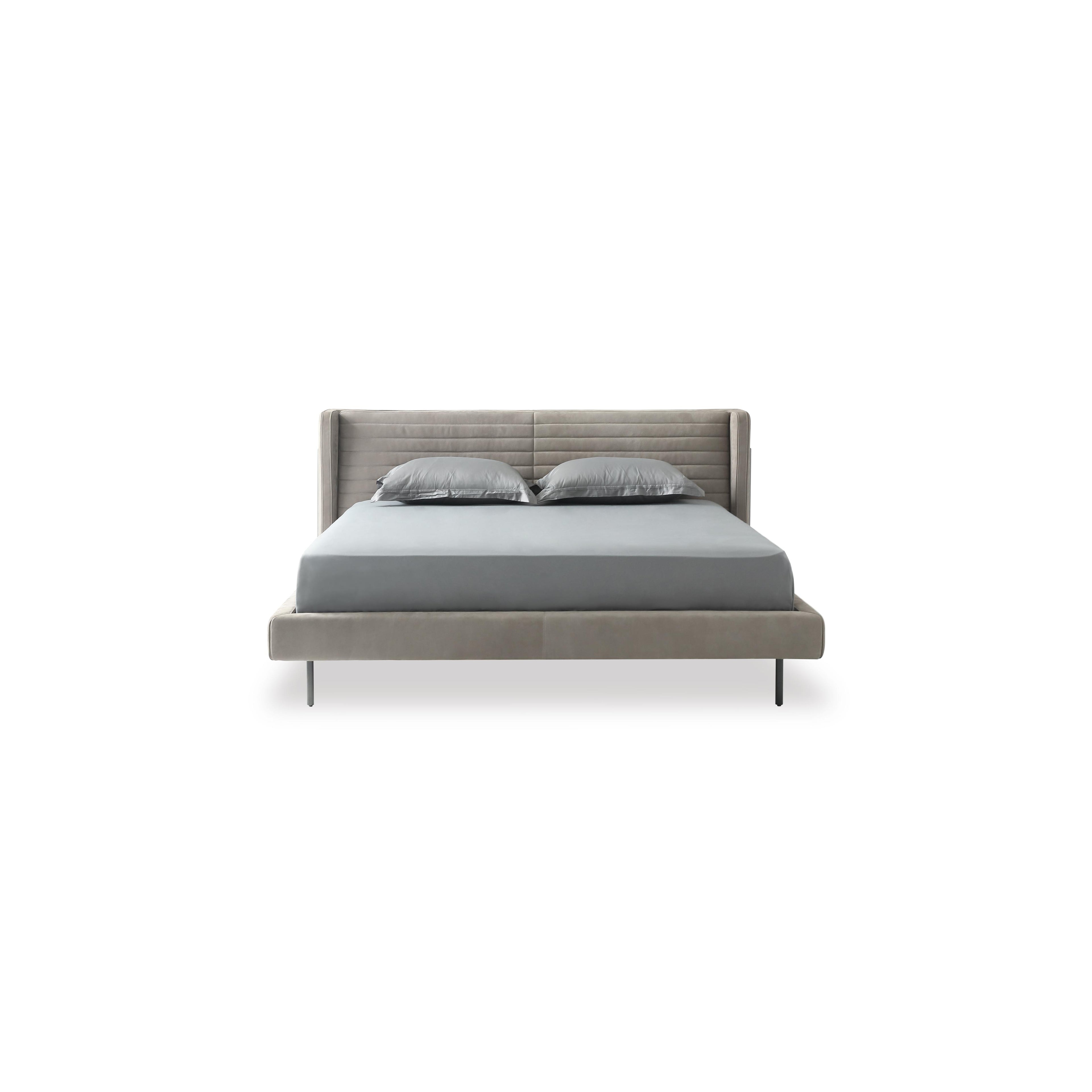 A modern bed with a gray upholstered headboard and base, supported by four thin black legs. It features a tufted backrest, layered pillows, and a satin-textured duvet. Designed for sleeping, it has a clean, minimalist silhouette with visible stitching along seams. Category: Furniture > Beds > Modern Beds