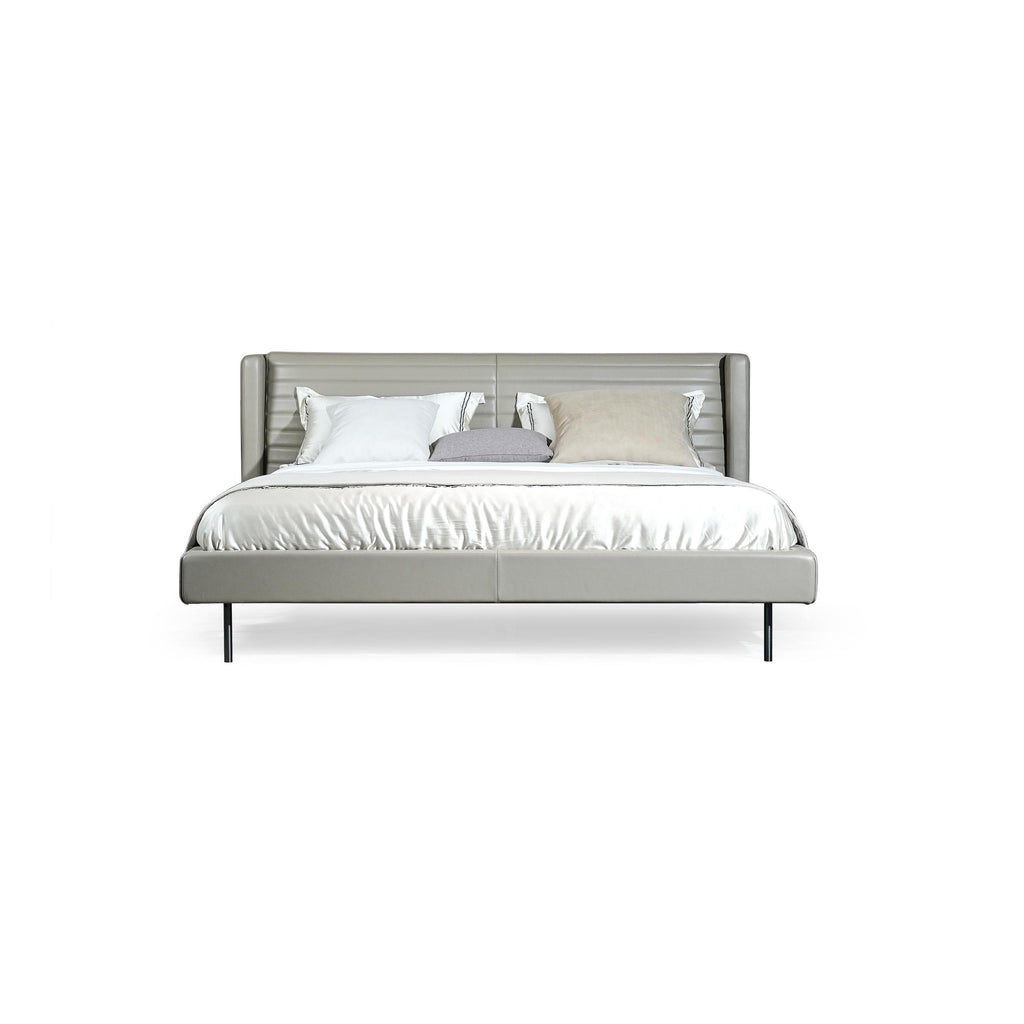 A modern bed with a gray upholstered headboard and base, supported by four thin black legs. It features a tufted backrest, layered pillows, and a satin-textured duvet. Designed for sleeping, it has a clean, minimalist silhouette with visible stitching along seams. Category: Furniture > Beds > Modern Beds