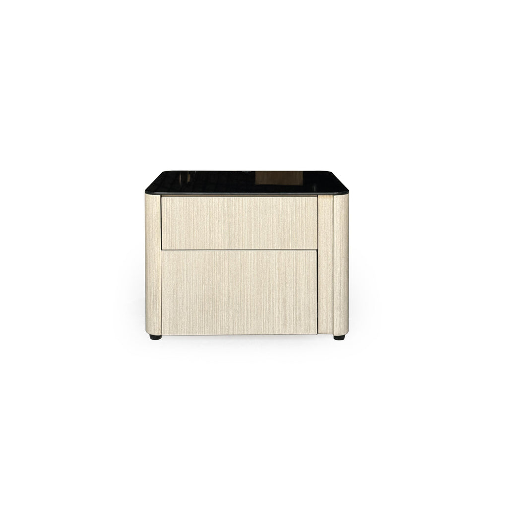 This is a two-drawer nightstand with a black glossy top and light wood-grain sides. It has rounded corners, four small black feet, and no visible handles. Designed for bedside storage, it features a flat front with vertical grain texture. Category: furniture/nightside-tables