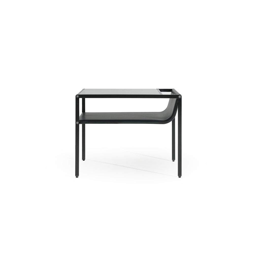 Black metal-framed side table with glass top and lower shelf, featuring curved leather-like surface on the shelf. Four straight legs support the structure. Designed for holding items or as a decorative piece. Category: furniture/side-tables