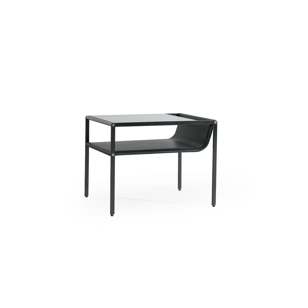 Black metal-framed side table with glass top and lower shelf, featuring curved leather-like surface on the shelf. Four straight legs support the structure. Designed for holding items or as a decorative piece. Category: furniture/side-tables