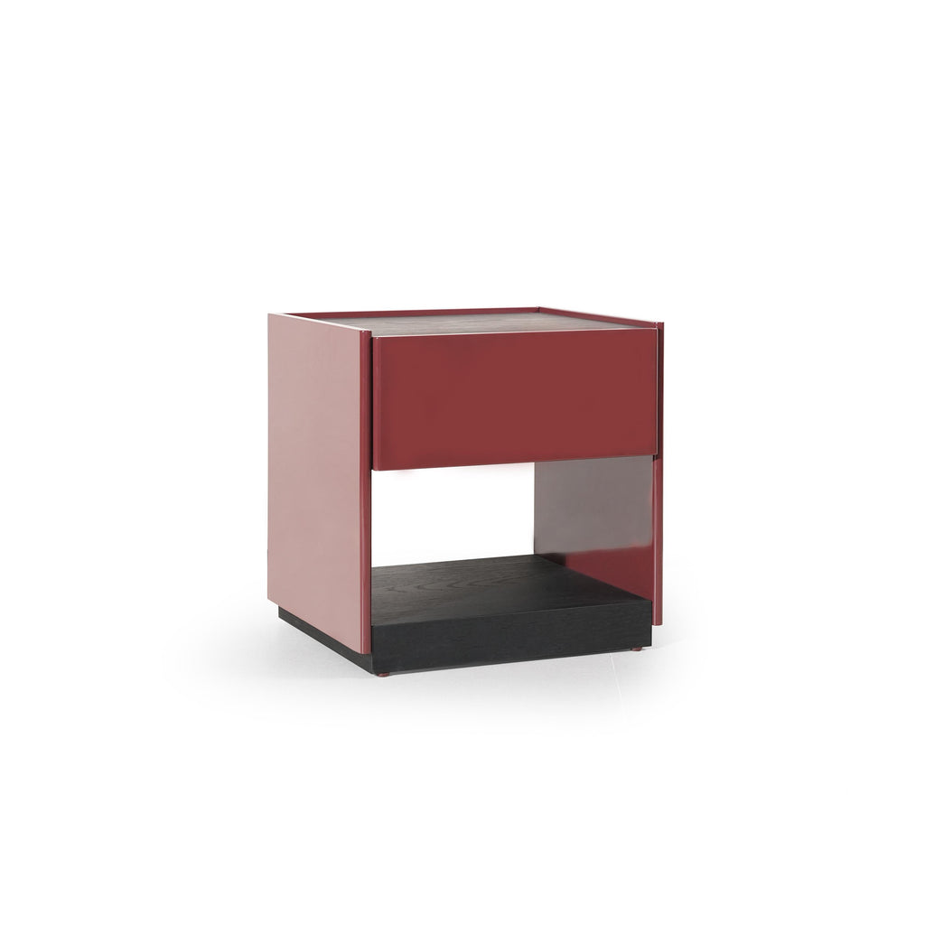 This is a modern side table with a rectangular top, red-painted frame, and a dark wood base. It features a single drawer and an open shelf below. The table has four vertical legs and a visible wood grain texture on the base. Intended for bedside or room storage, it stands upright with clean lines and contrasting color sections. Category: Furniture > Tables > Side Tables