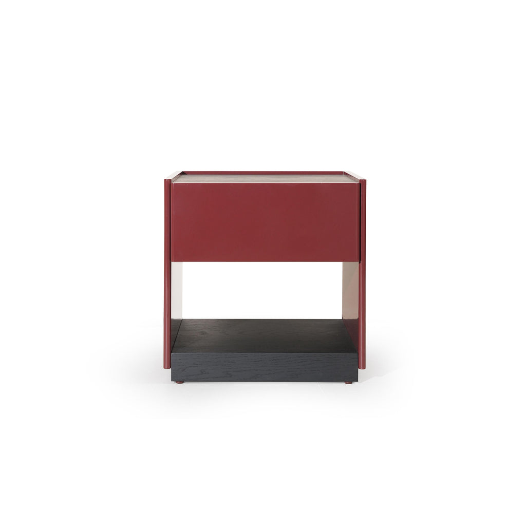 This is a modern side table with a rectangular top, red-painted frame, and a dark wood base. It features a single drawer and an open shelf below. The table has four vertical legs and a visible wood grain texture on the base. Intended for bedside or room storage, it stands upright with clean lines and contrasting color sections. Category: Furniture > Tables > Side Tables