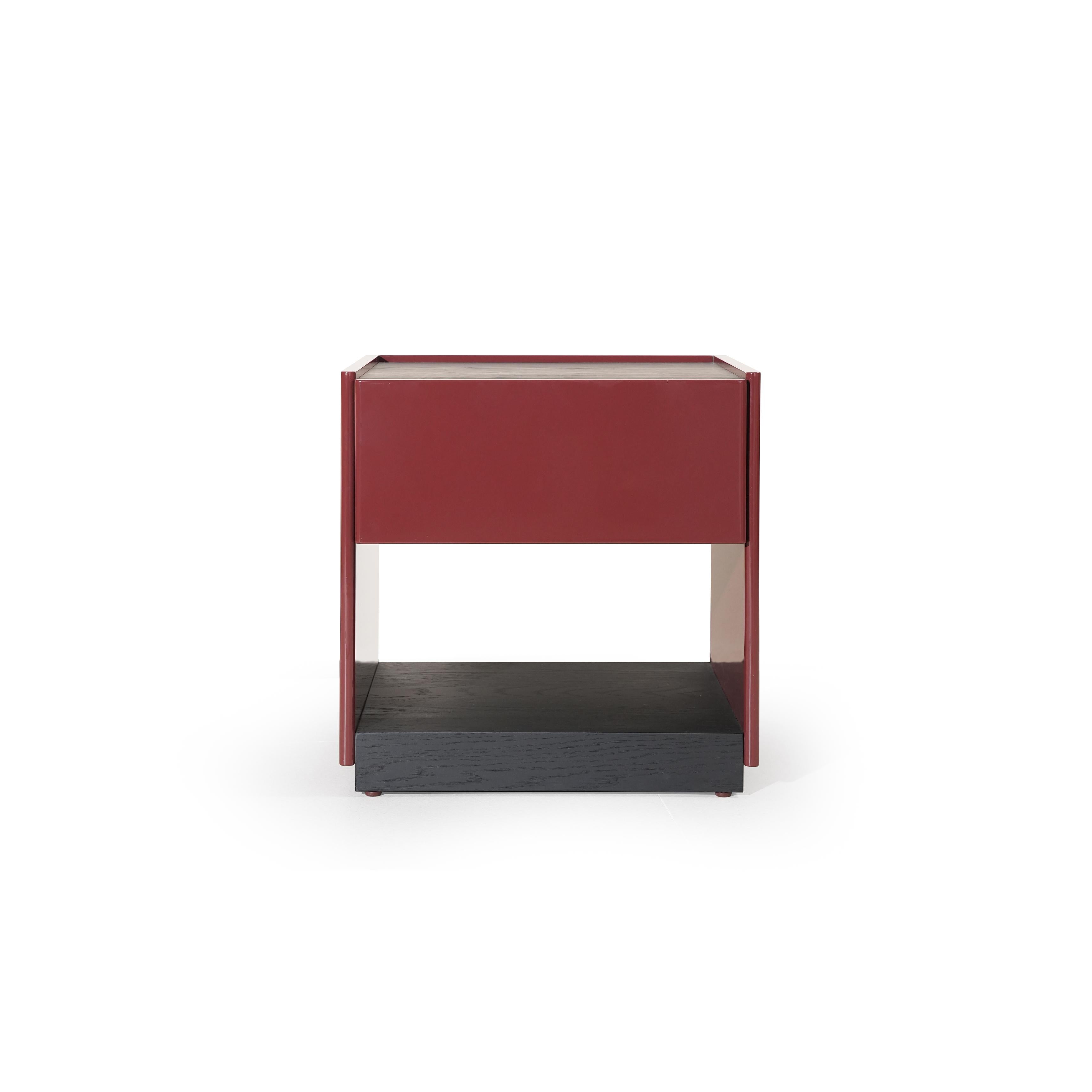 This is a modern side table with a rectangular top, red-painted frame, and a dark wood base. It features a single drawer and an open shelf below. The table has four vertical legs and a visible wood grain texture on the base. Intended for bedside or room storage, it stands upright with clean lines and contrasting color sections. Category: Furniture > Tables > Side Tables