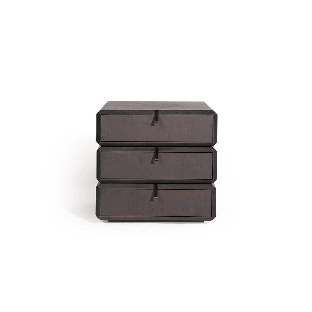 Three-drawer nightstand with dark wood finish and visible grain, each drawer fitted with a black metal pull handle; compact, stacked rectangular form; intended for bedside storage; Category: furniture > bedroom > nightstands