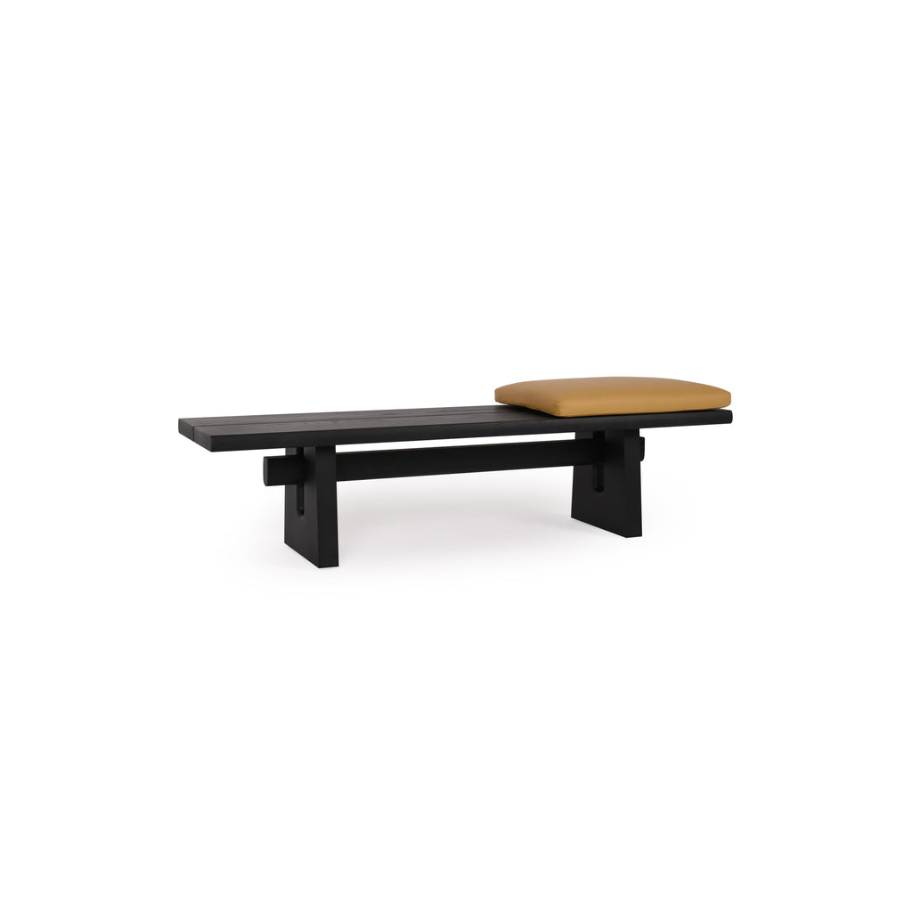Black wooden bench with a single mustard-colored cushion resting on its seat. Features thick, blocky legs and a horizontal support beam beneath the seat. No arms, backrest, or drawers. Intended for seating. Category: furniture/benches