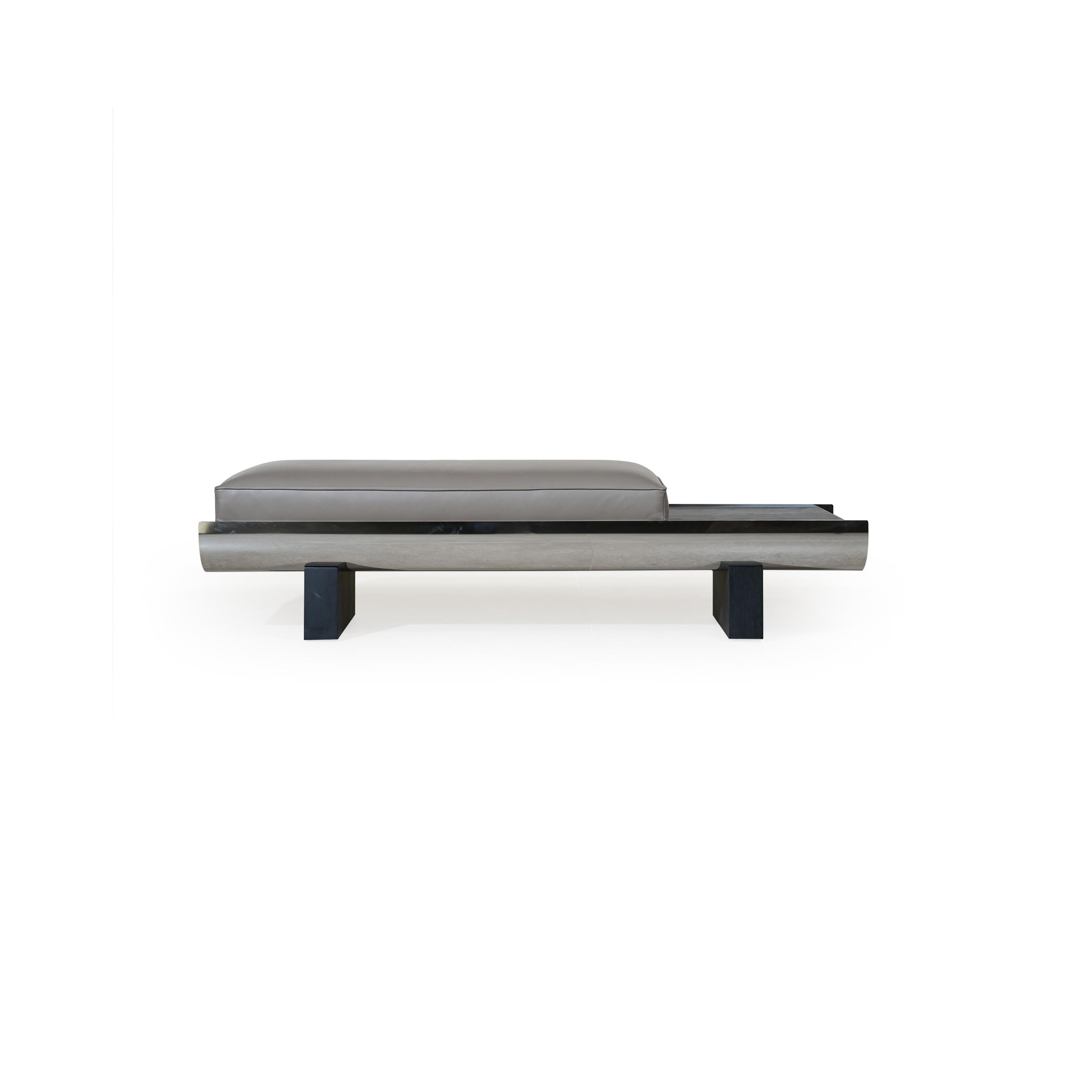 Modern bench with rectangular cushioned seat in gray upholstery, supported by a sleek metallic frame and dark wooden legs; features a curved front edge and a horizontal metallic strip along the base; designed for seating or as a low-profile accent piece. Category: Furniture > Benches
