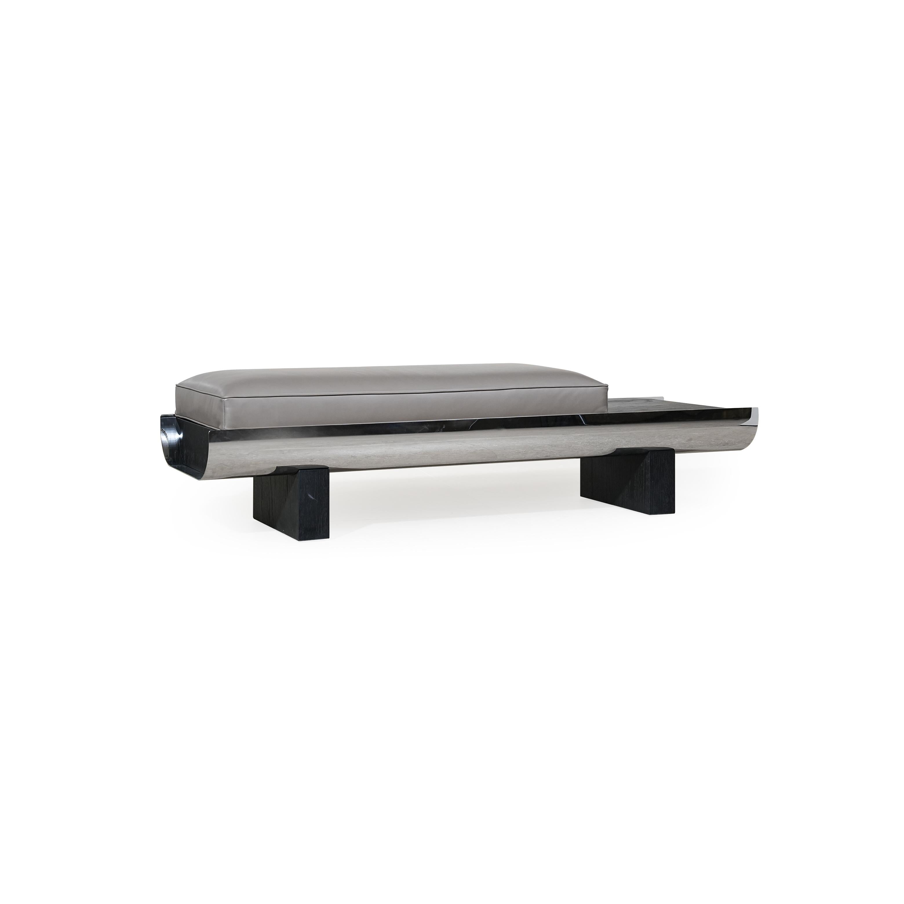 Modern bench with rectangular cushioned seat in gray upholstery, supported by a sleek metallic frame and dark wooden legs; features a curved front edge and a horizontal metallic strip along the base; designed for seating or as a low-profile accent piece. Category: Furniture > Benches