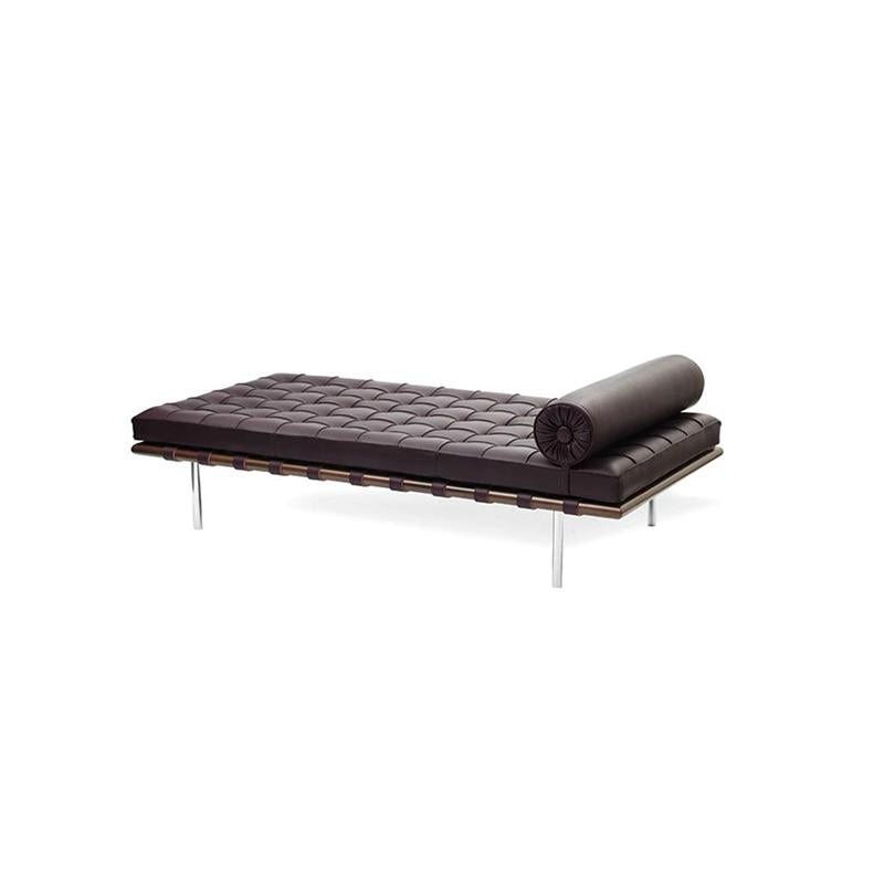 Dark brown upholstered chaise lounge with tufted surface and rolled cylindrical pillow; supported by slender metal legs and a wooden frame with horizontal straps; designed for reclining or lounging; Category: Furniture > Sofas & Loungers > Chaise Lounges