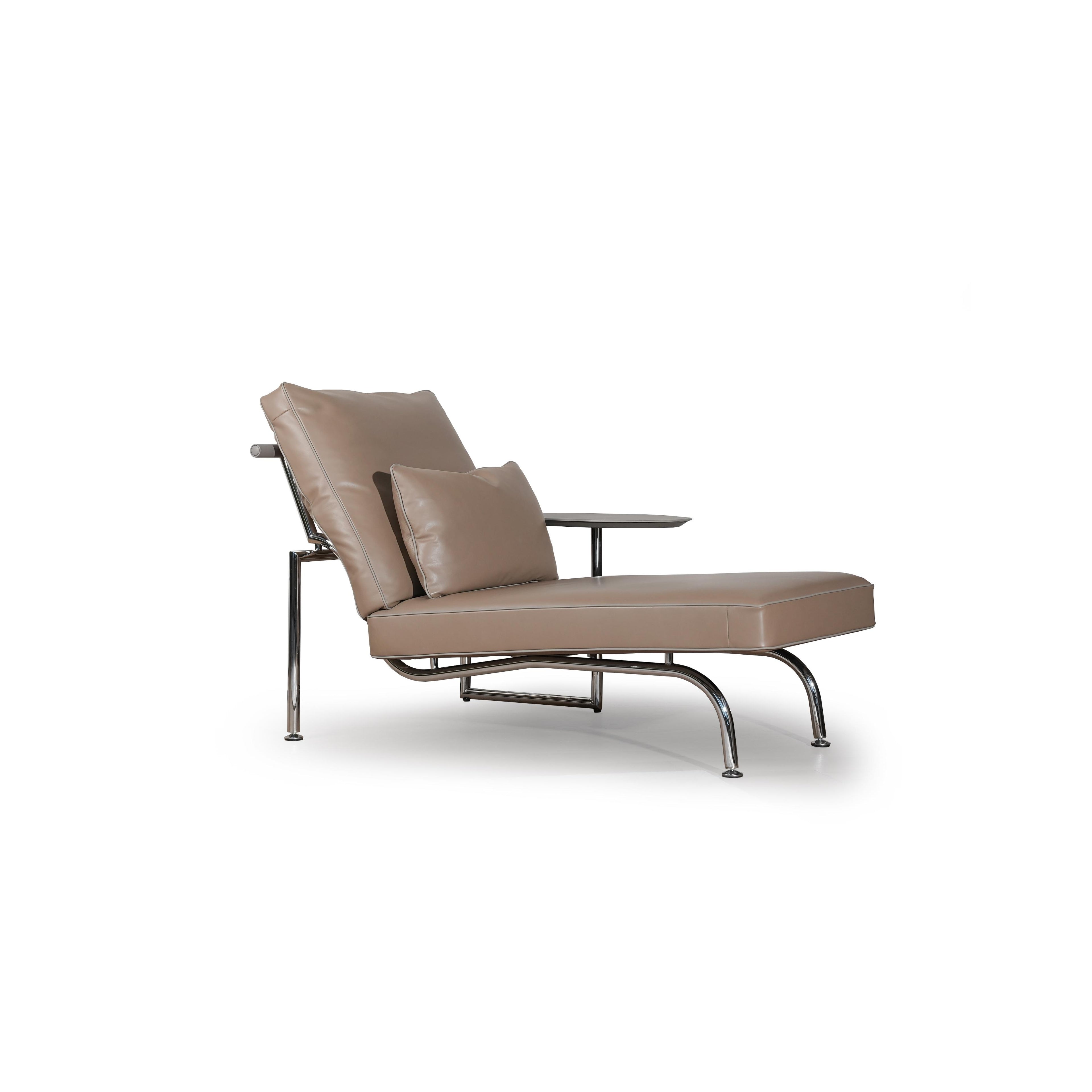 Modern armchair with tan upholstered seat and backrest, featuring a small matching cushion, chrome-finished legs, and a side table attached to the right armrest. The chair has a sleek, minimalist form with visible stitching along seams. Intended for seated relaxation or reading. Category: Furniture > Chairs > Armchairs