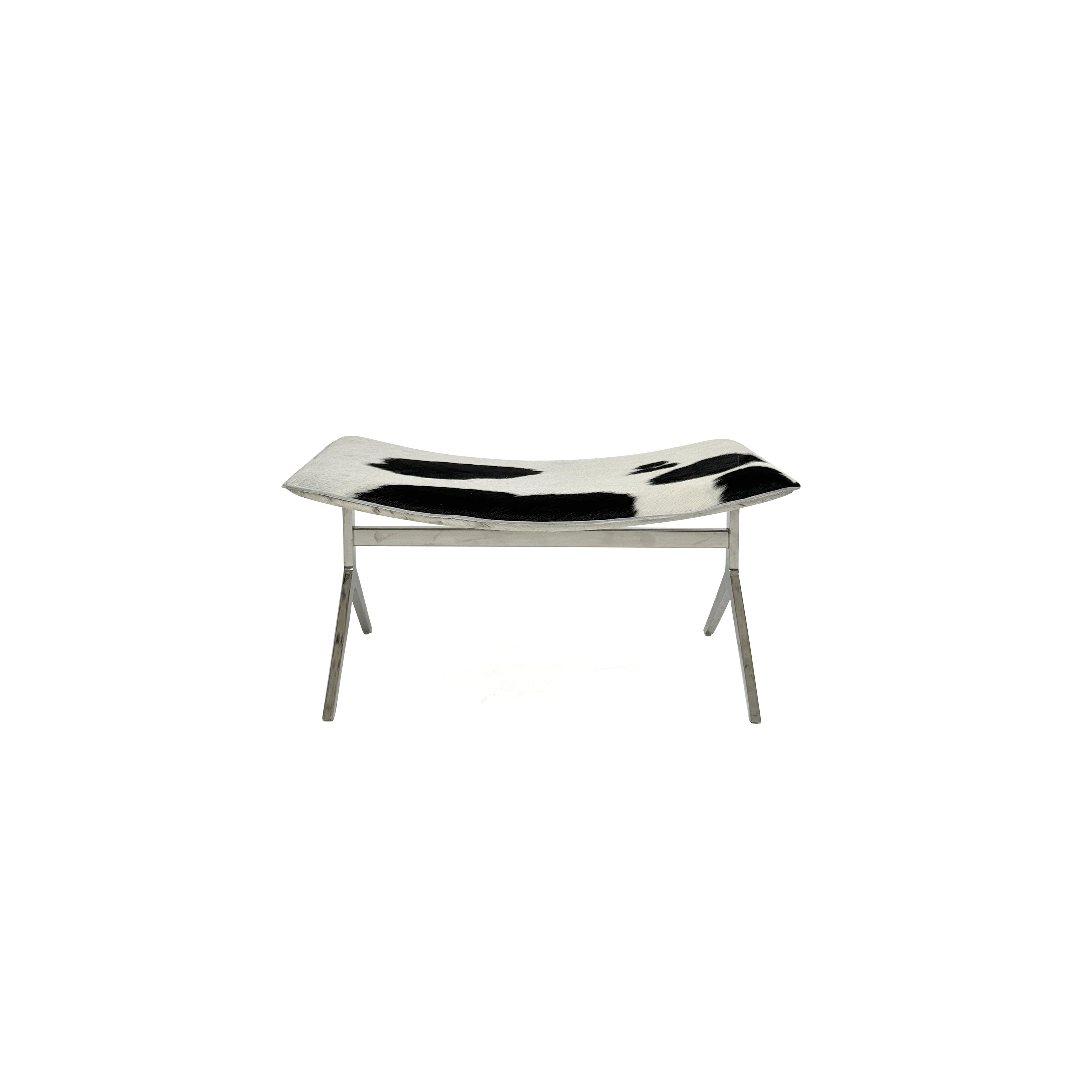 This is a modern lounge chair with a black and white cowhide upholstery on the seat and backrest, supported by a sleek, metallic X-shaped base. The chair has no arms or cushions, and its structure is minimalist. Intended for casual seating, it features a flat, continuous surface for comfort. Category: Furniture > Chairs > Lounge Chairs