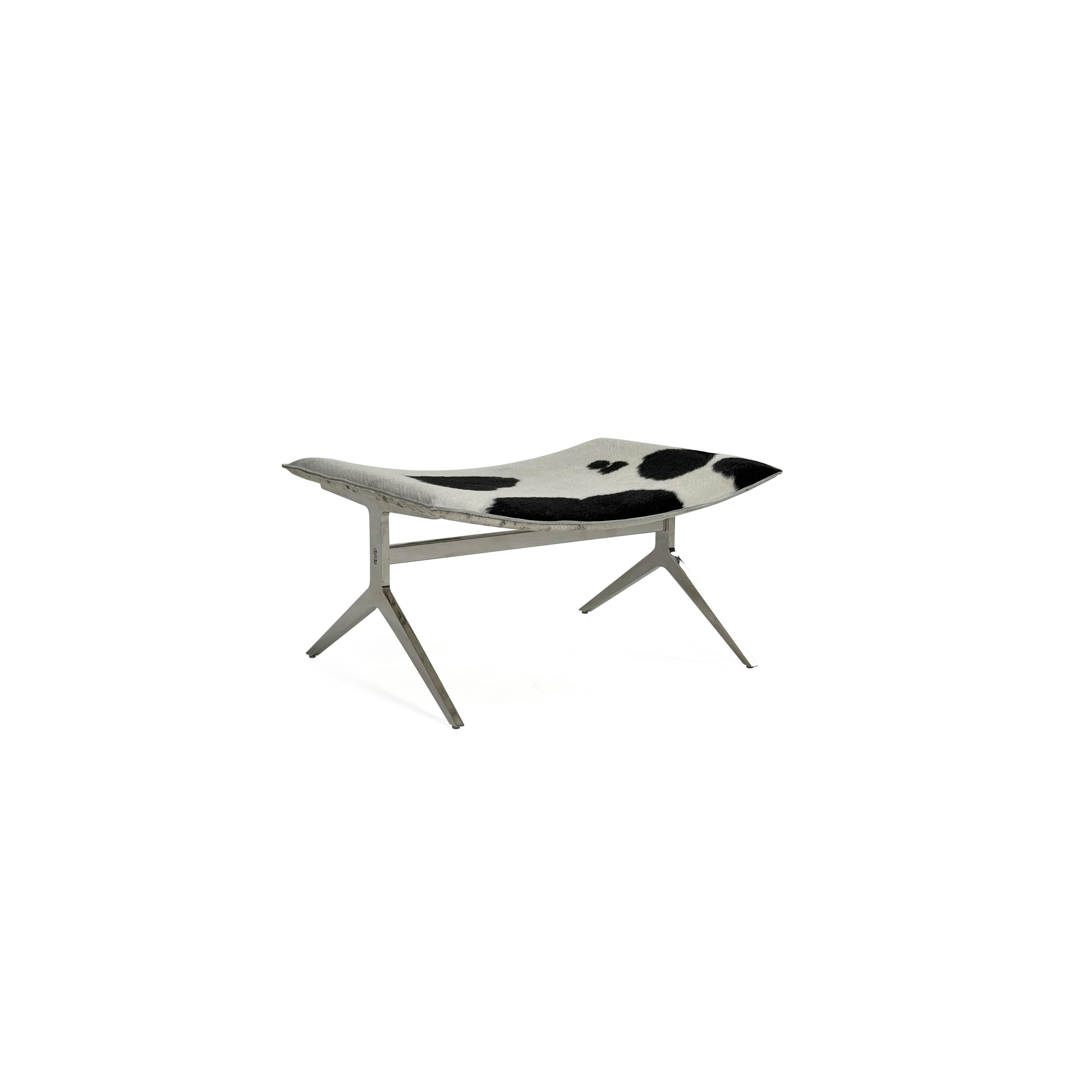 This is a modern lounge chair with a black and white cowhide upholstery on the seat and backrest, supported by a sleek, metallic X-shaped base. The chair has no arms or cushions, and its structure is minimalist. Intended for casual seating, it features a flat, continuous surface for comfort. Category: Furniture > Chairs > Lounge Chairs