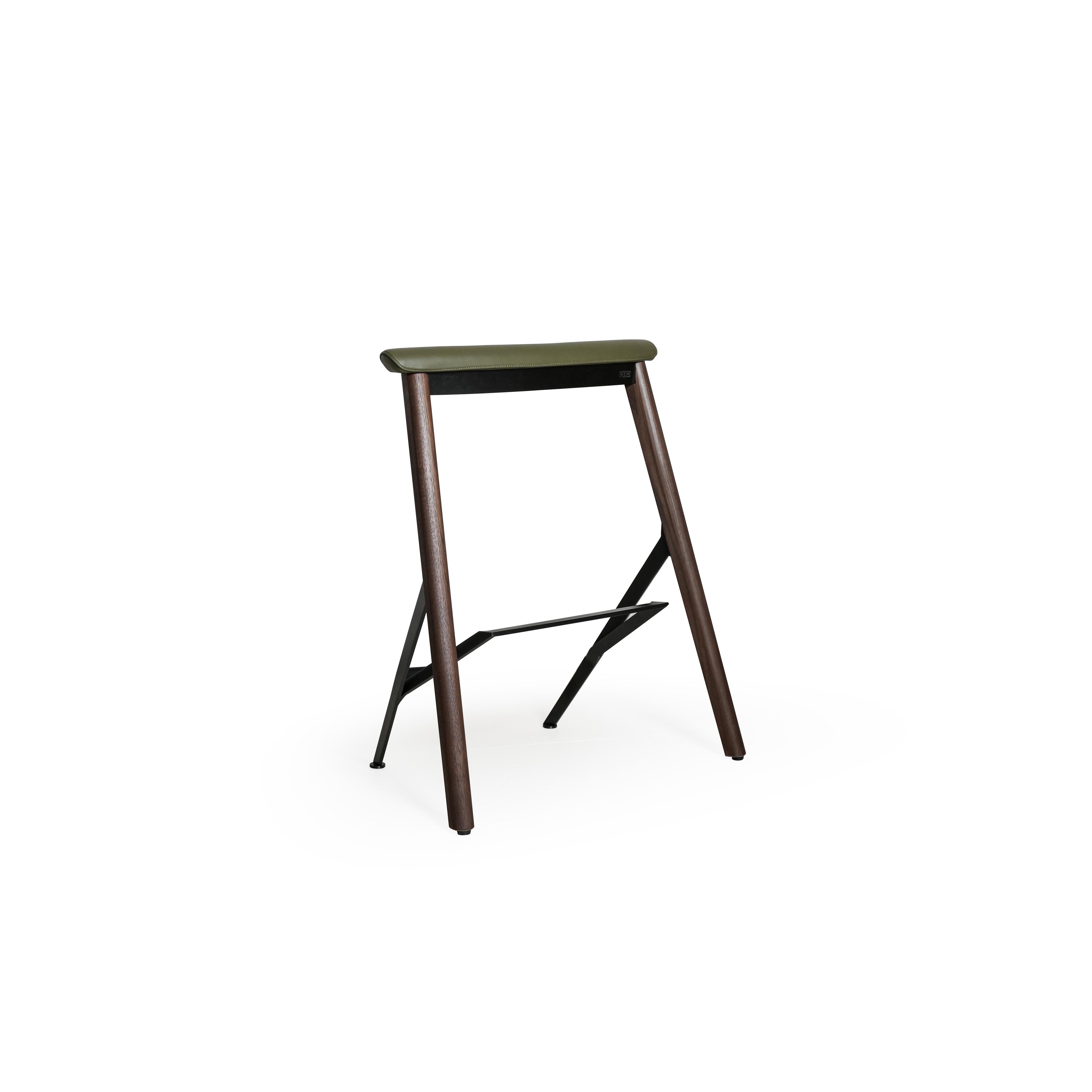 This is a bar stool with an olive green upholstered seat, dark wood legs, and a metal frame with a footrest. The seat has visible stitching. It’s designed for sitting at counters or tables. Category: furniture/stools