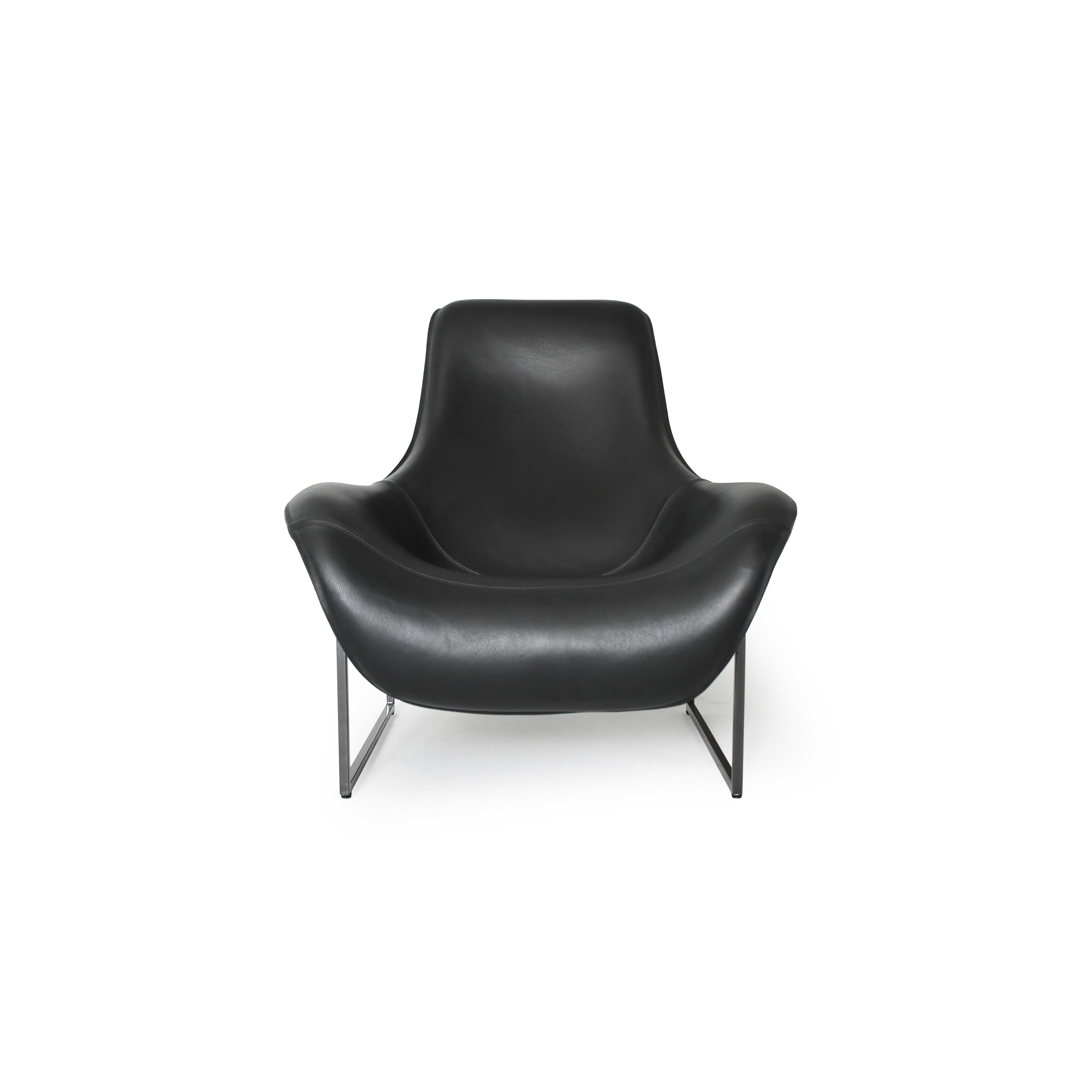 Black leather-like upholstered armchair with curved backrest and integrated armrests, supported by slender metal legs; minimalist form designed for seated comfort in living or reading spaces. Category: furniture/chairs/armchairs