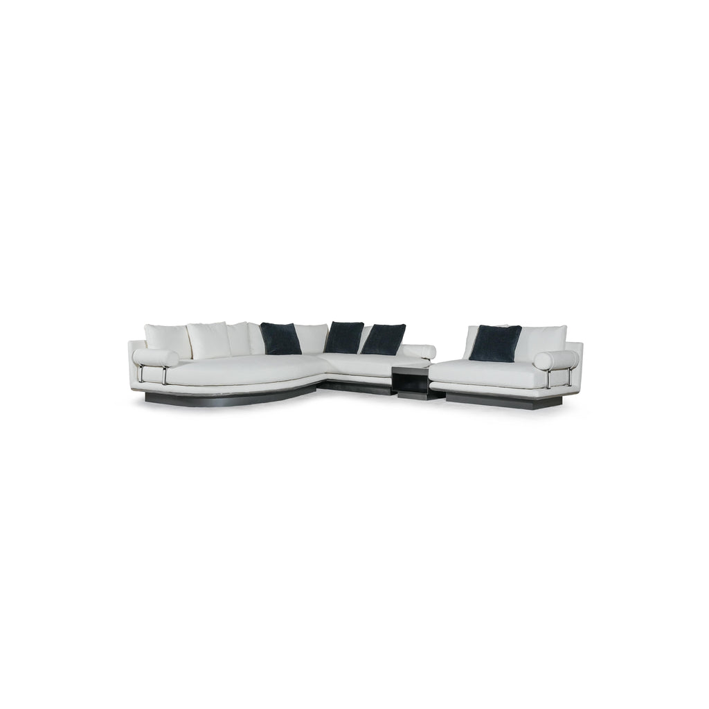 Modern sectional sofa with white upholstered cushions and dark navy throw pillows; L-shaped configuration with rounded arms, low-profile black base, and visible metal frame supports; designed for seating and lounging; Category: furniture > sofas > sectional sofas