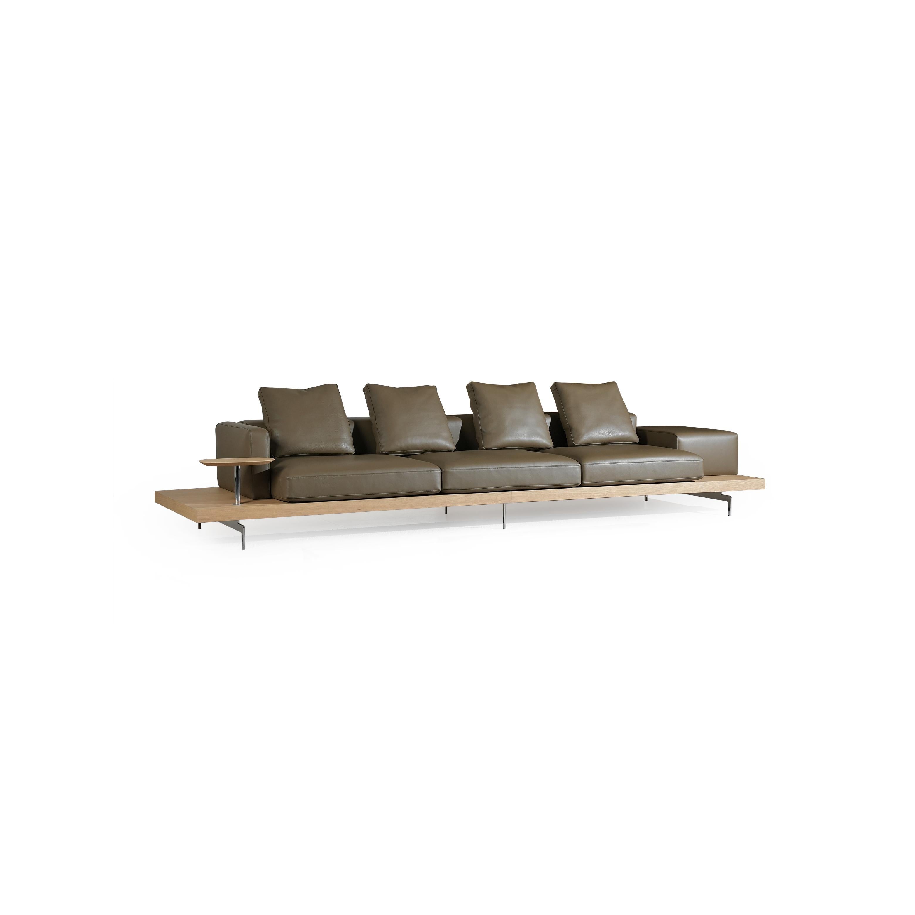 Modern sofa with four seat cushions and four back cushions in brown leather-like finish, supported by a light wood platform and thin metal legs; includes a small side table on the left; designed for seating and lounging. Category: furniture/sofas