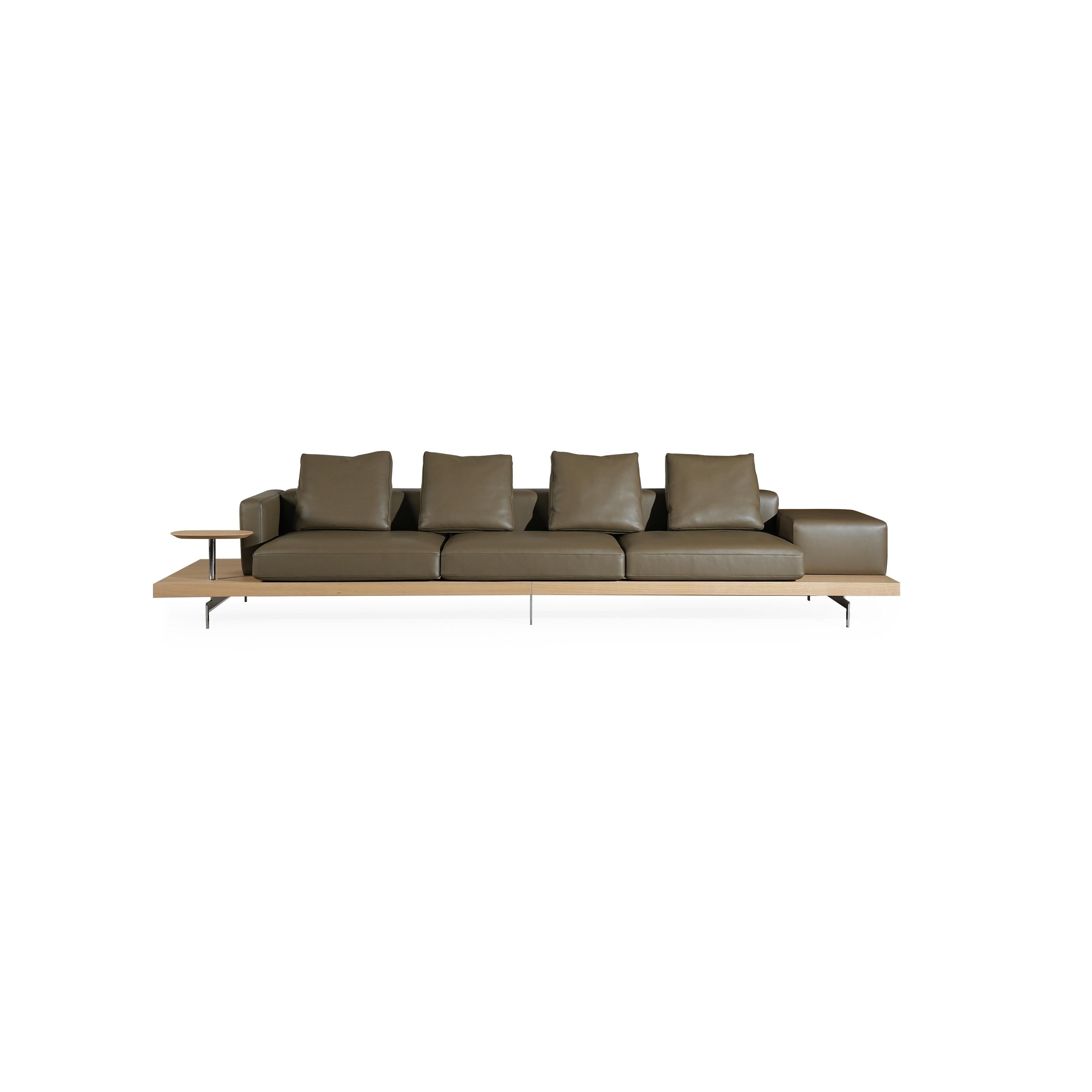 Modern sofa with four seat cushions and four back cushions in brown leather-like finish, supported by a light wood platform and thin metal legs; includes a small side table on the left; designed for seating and lounging. Category: furniture/sofas