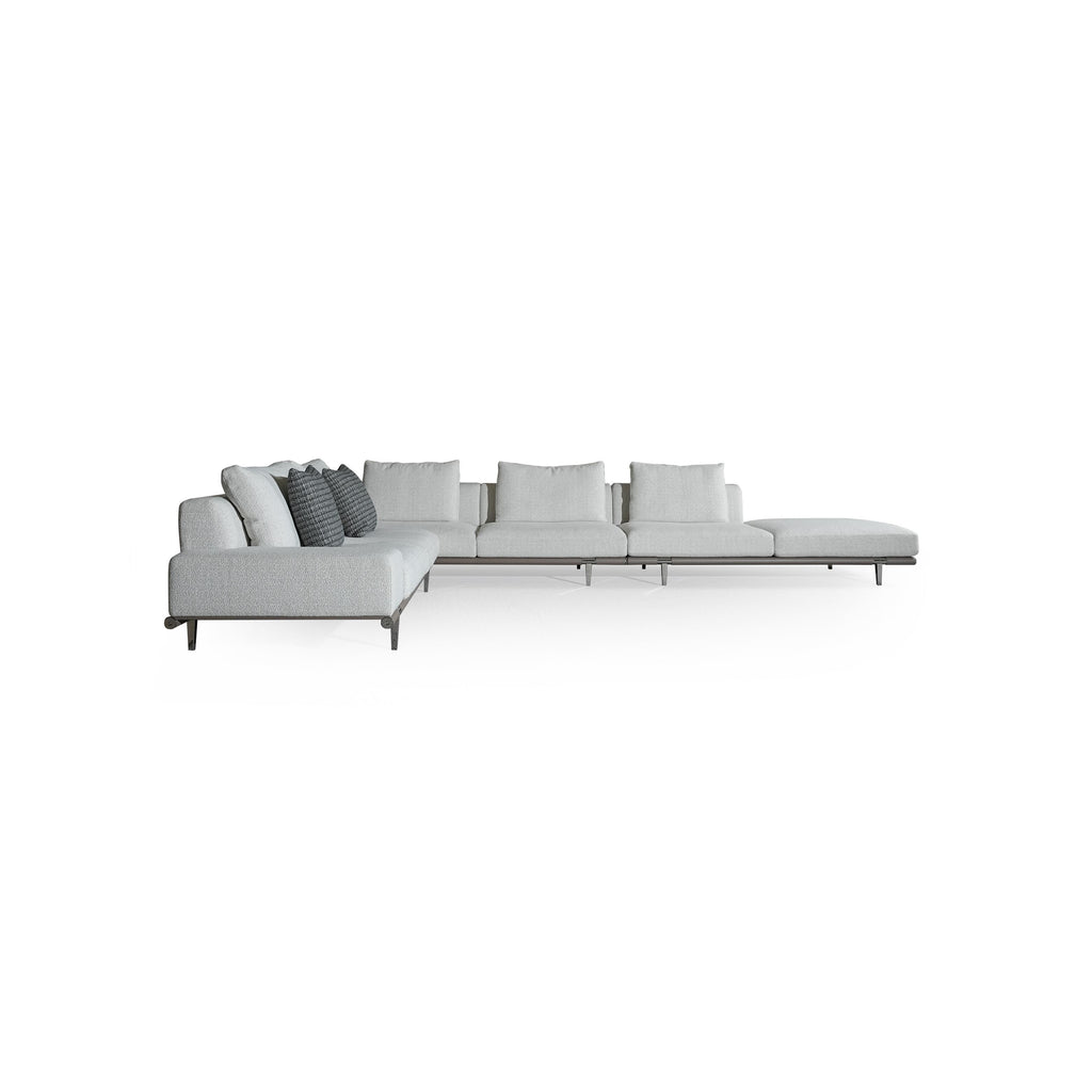 Modern sectional sofa with light gray fabric upholstery, low-profile metal legs, segmented backrest and seat cushions, and two dark patterned throw pillows; designed for lounging and seating in open spaces. Category: furniture/sofas