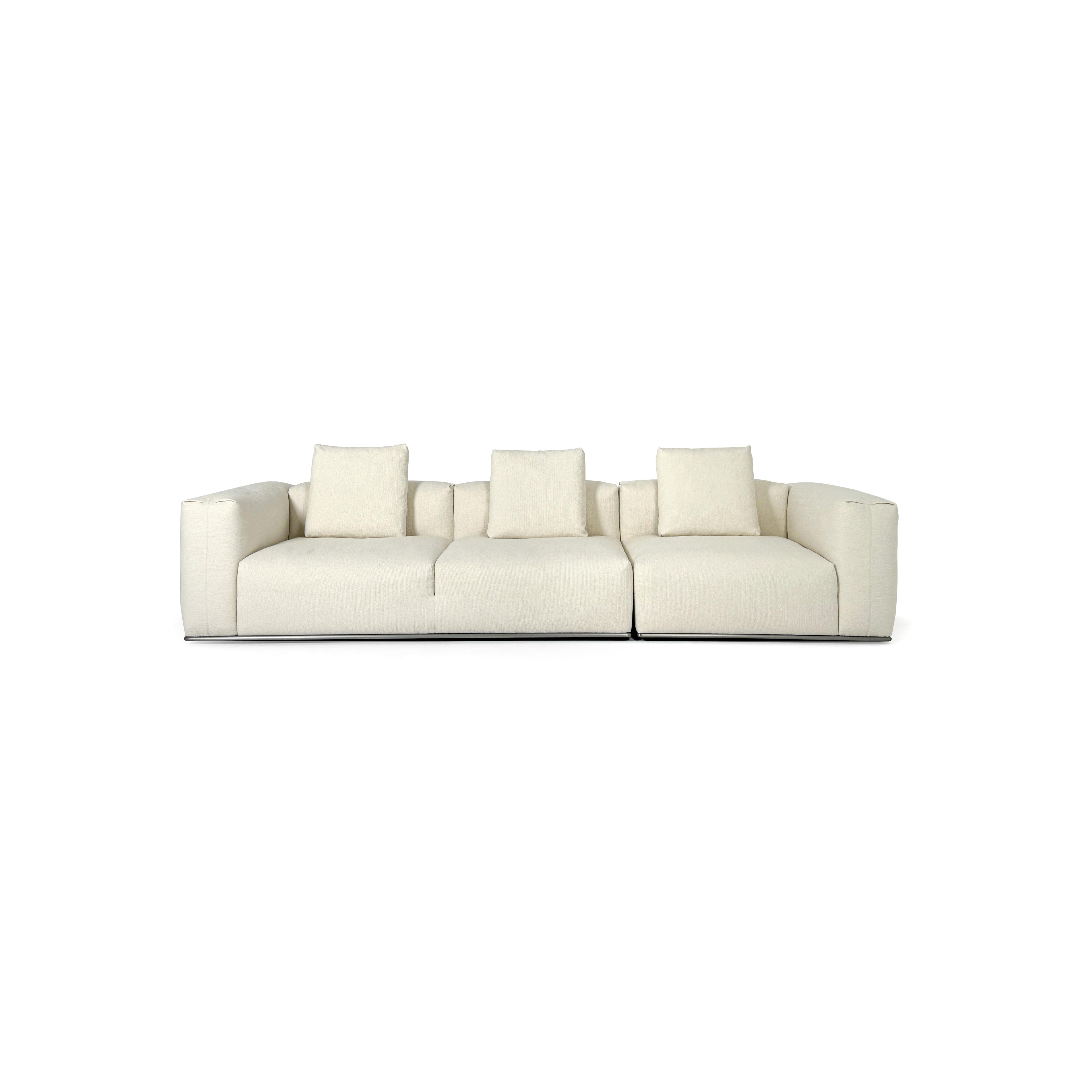 A three-seater sofa with off-white fabric upholstery, featuring segmented cushions, squared arms, and a low-profile metal base. It includes three matching back cushions. Designed for seating, it has a clean, modular form with visible stitching and no visible fasteners or handles. Category: Furniture > Sofas > Sectionals