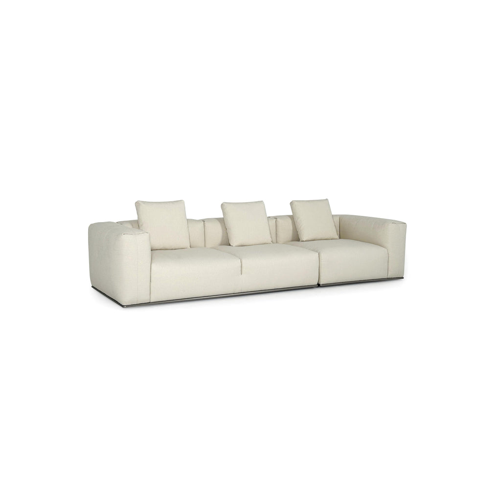 A three-seater sofa with off-white fabric upholstery, featuring segmented cushions, squared arms, and a low-profile metal base. It includes three matching back cushions. Designed for seating, it has a clean, modular form with visible stitching and no visible fasteners or handles. Category: Furniture > Sofas > Sectionals