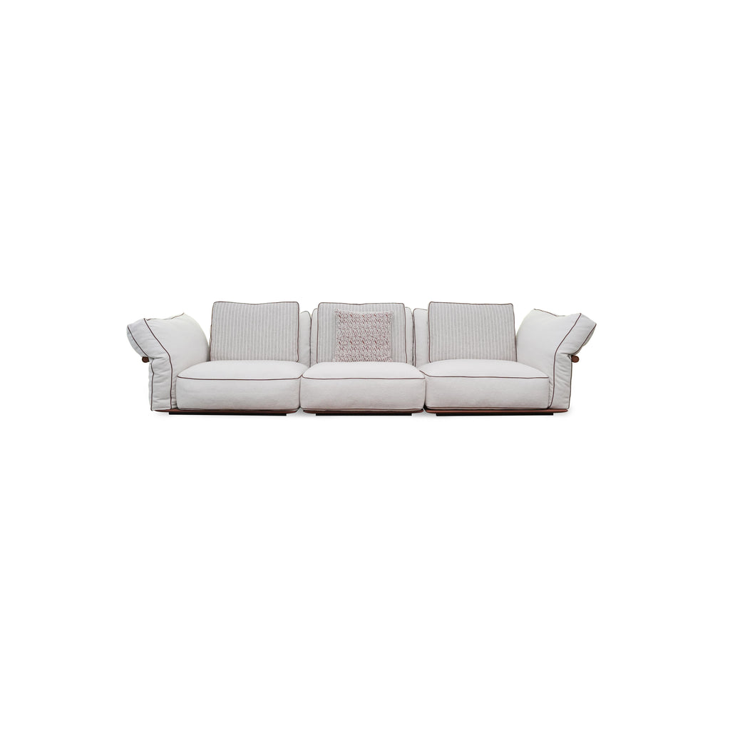 Three-seater sofa with light-colored fabric upholstery, striped back cushions, one textured throw pillow, padded armrests with dark trim, and low-profile dark wooden legs; designed for seating, featuring visible stitching and fabric texture. Category: furniture/southern-style-sofas