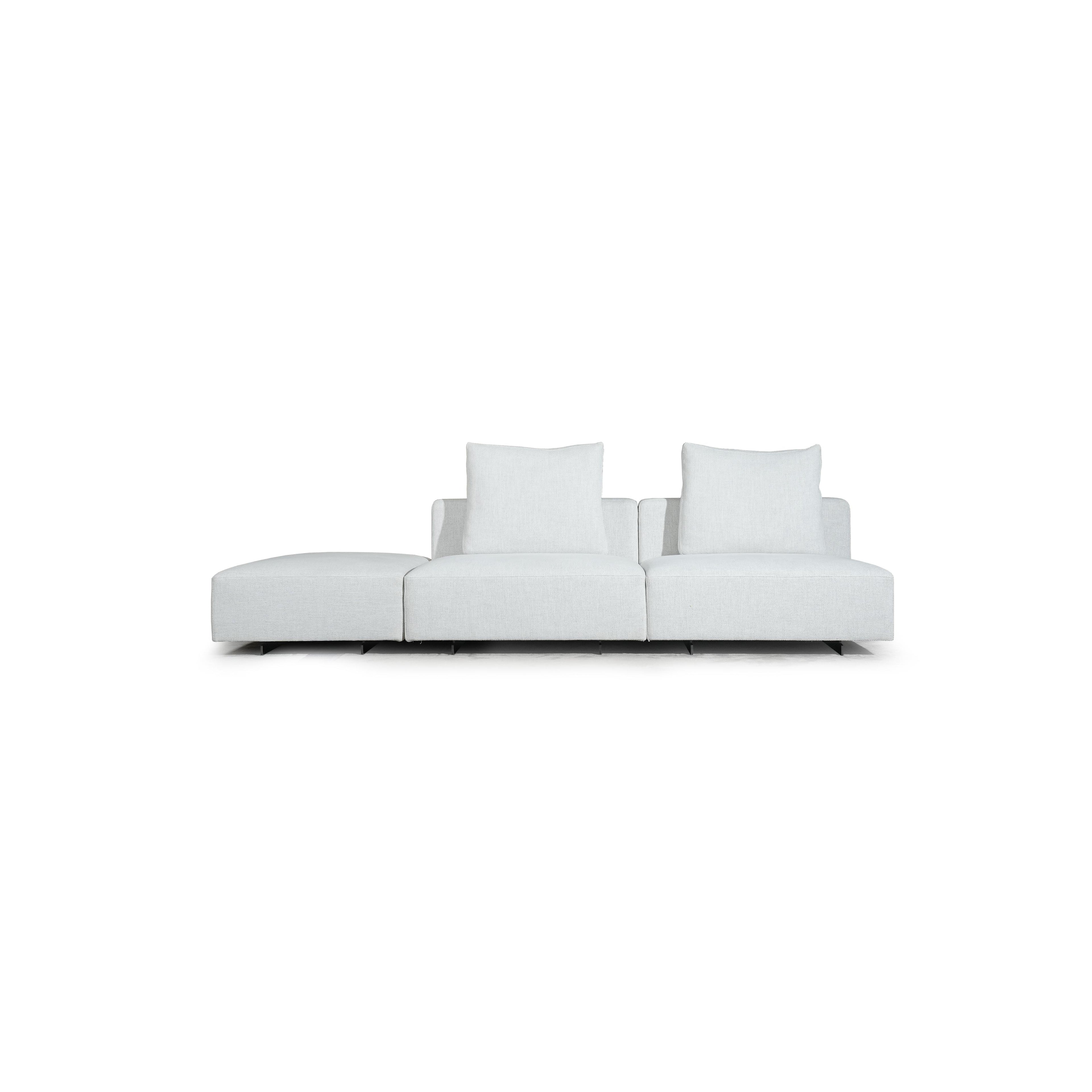 Brown leather-like sofa with three rectangular seat sections, two armrests, and two back cushions. Each section has a matching cushion. Right end features a wooden and dark gray panel. Supported by black legs. Intended for seating. Category: furniture/sofas