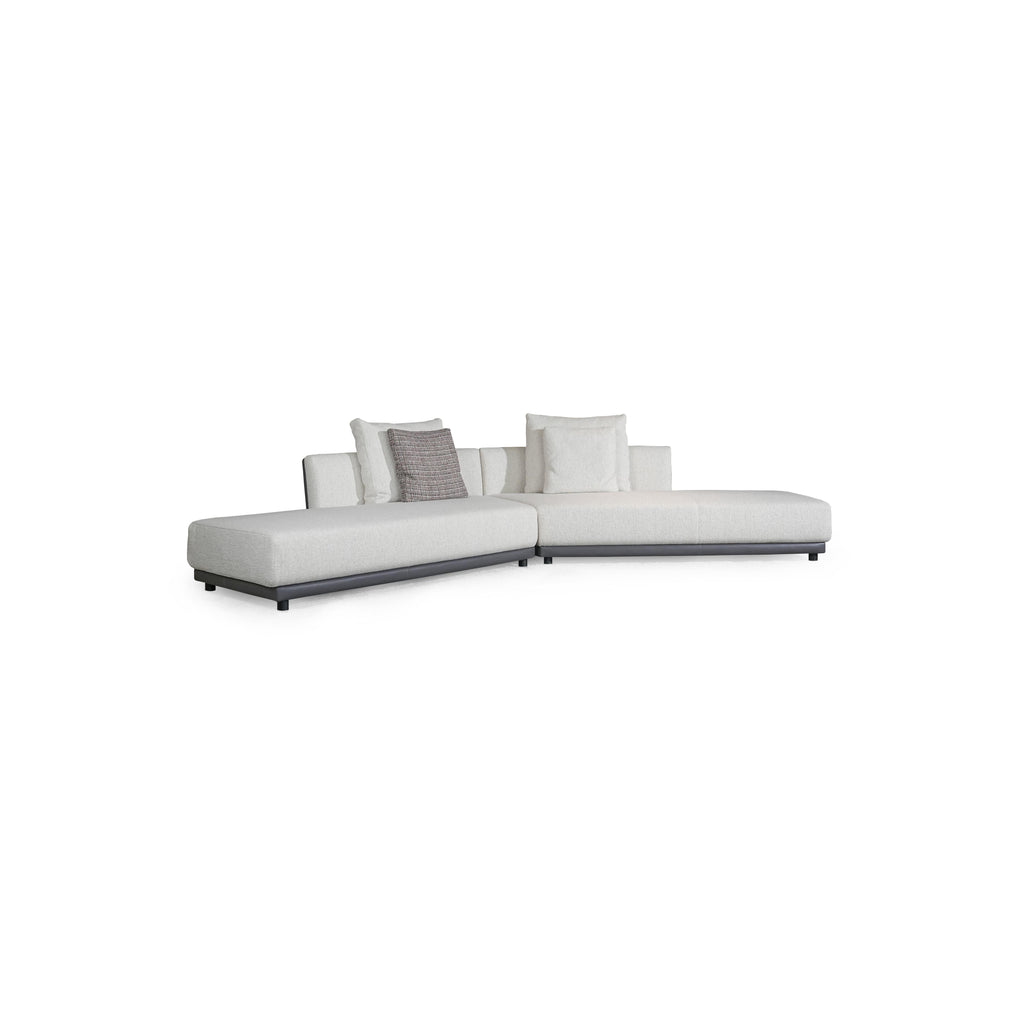 L-shaped sectional sofa with off-white fabric upholstery and dark gray armrests and base. Features multiple cushions, including two textured throw pillows. Supported by short, dark legs. Designed for seating and lounging. Category: furniture/sofas